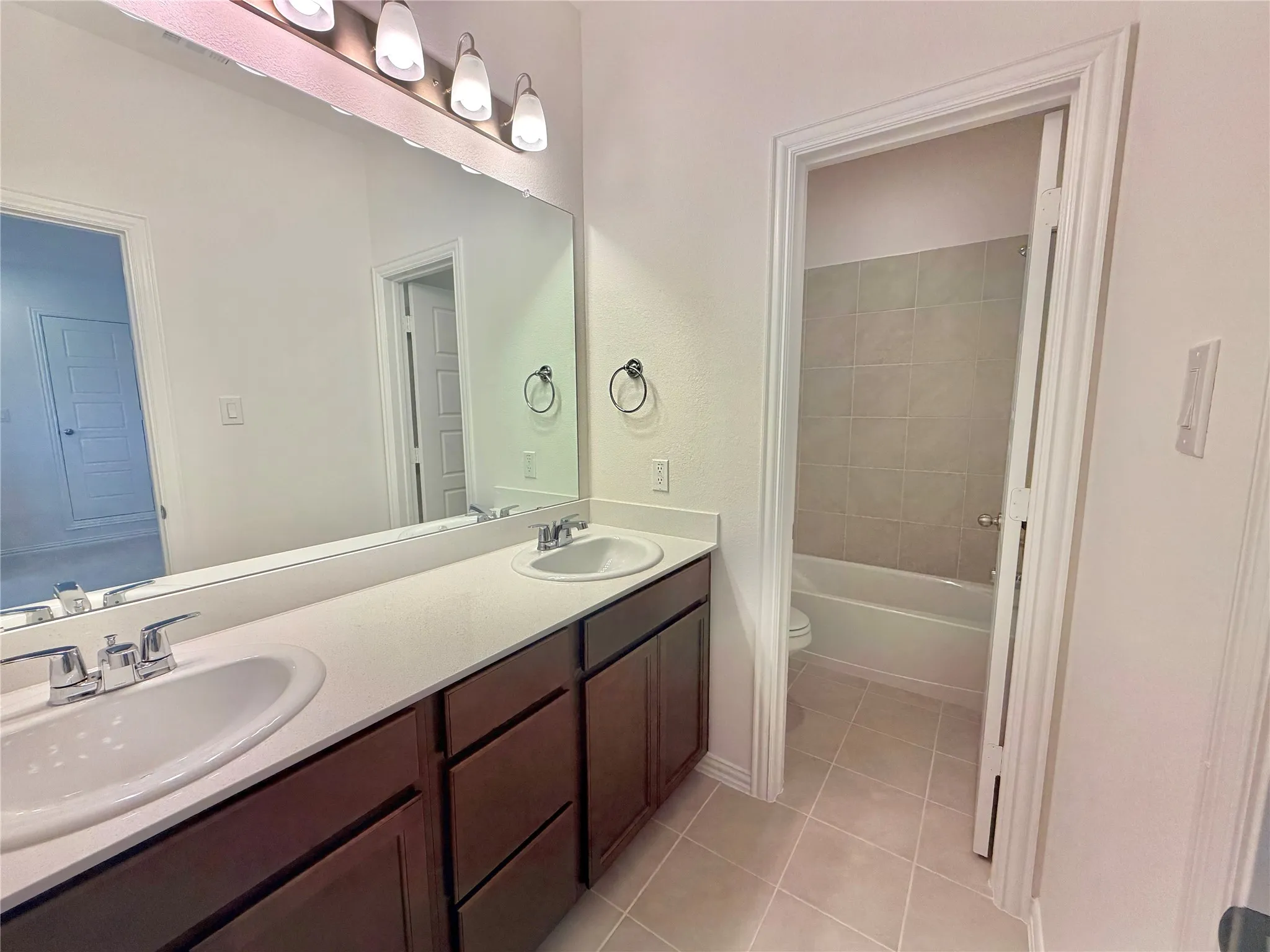 Double vanity with under-mount sinks and chrome faucets, integrated countertop, and rich wood-finish cabinetry