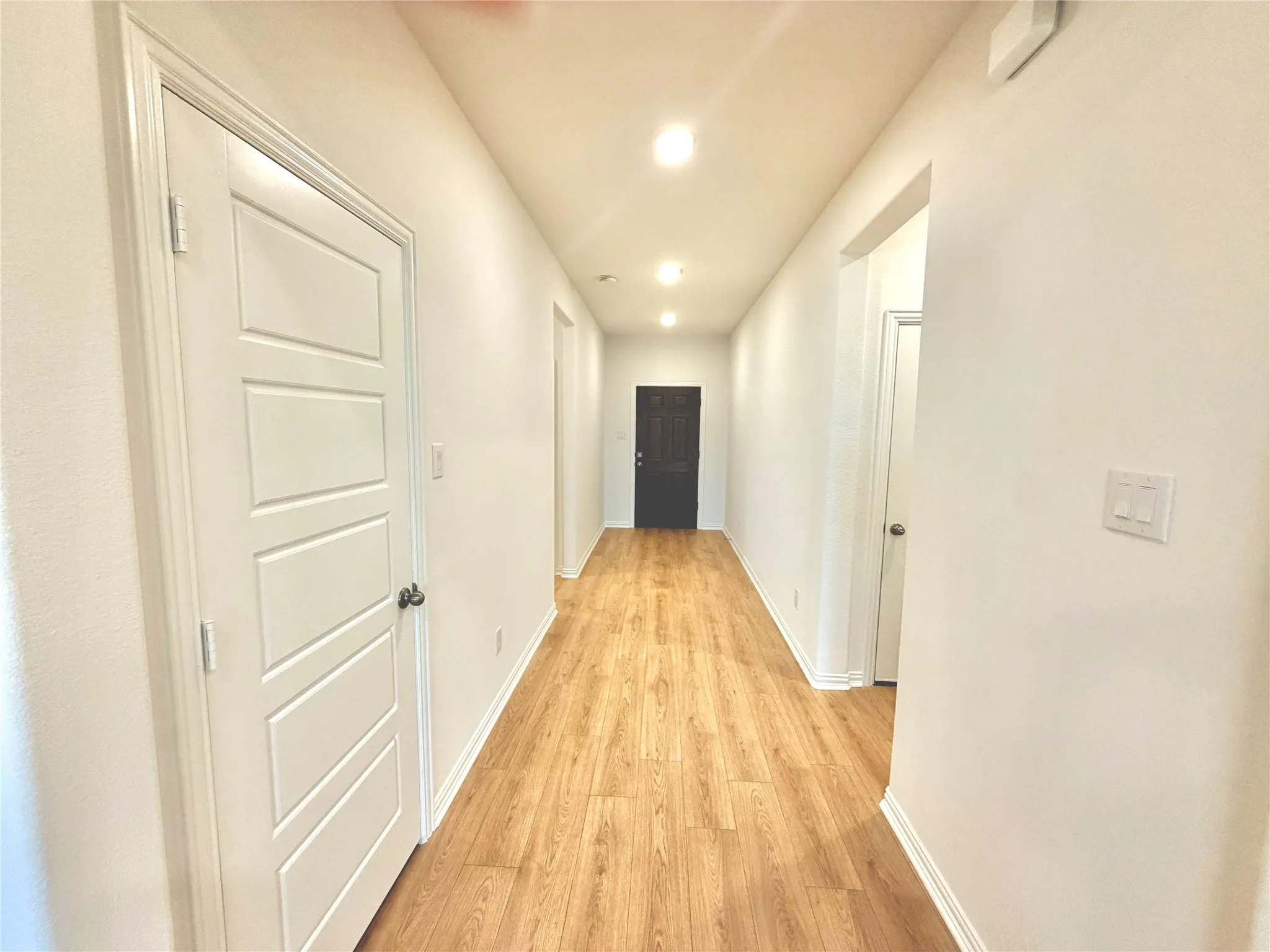 Hallway with wood-finish flooring, recessed lighting, and white paneled doors
