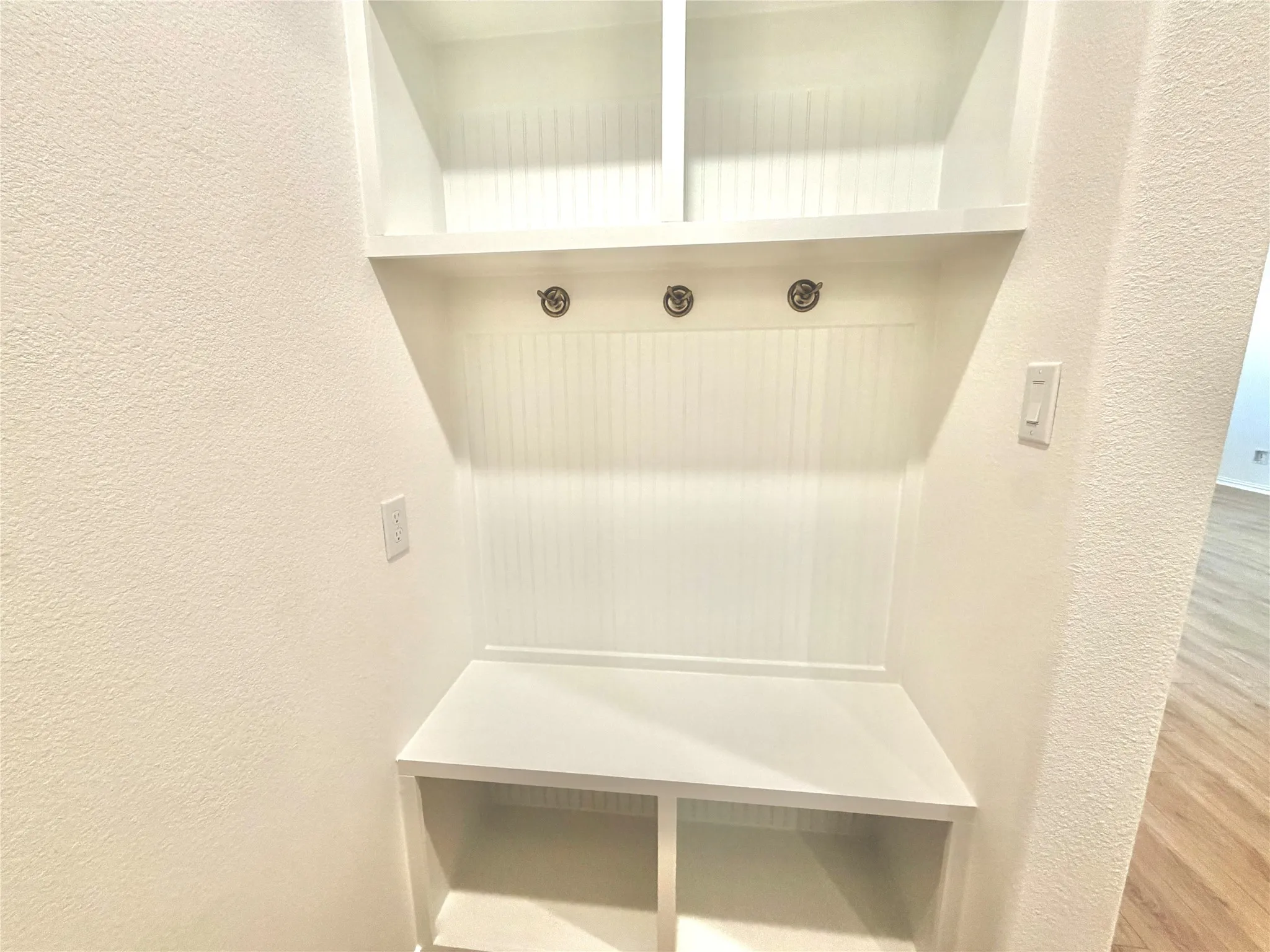 Built-in storage bench with overhead shelving and wall hooks