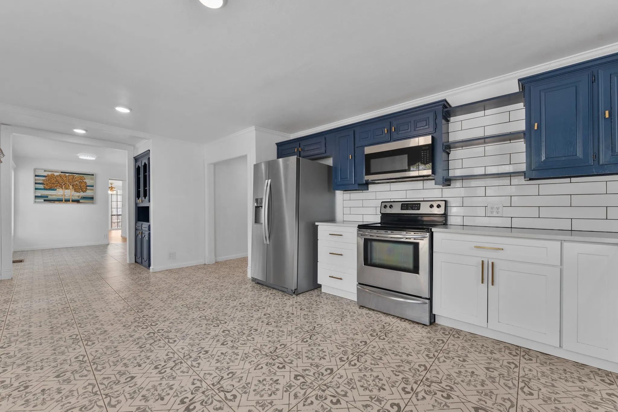 Kitchen featuring stainless steel appliances, white subway tile backsplash, white base cabinetry, and blue upper cabinetry