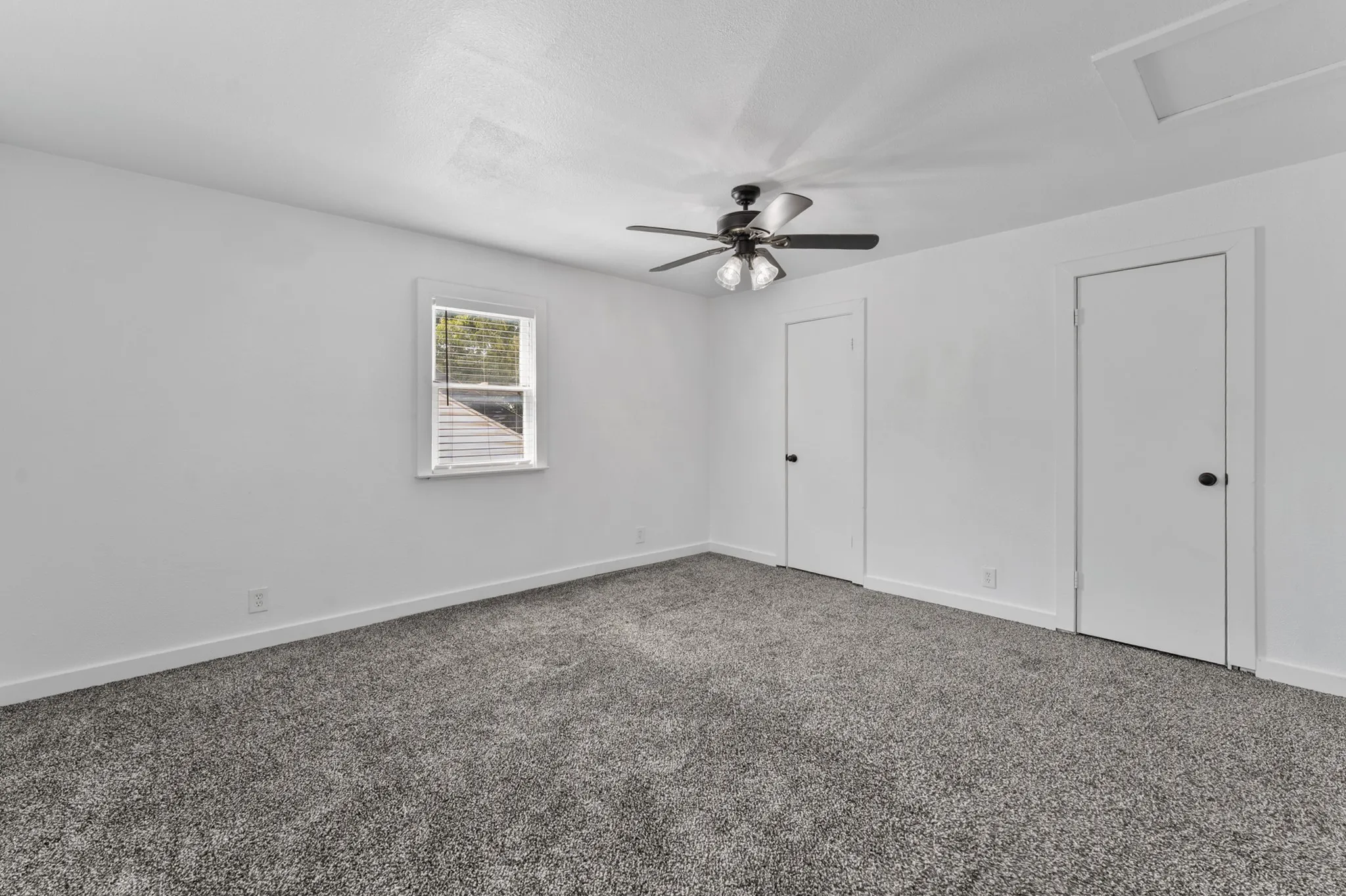 Room featuring textured carpeting, white walls, and a ceiling fan with integrated lighting