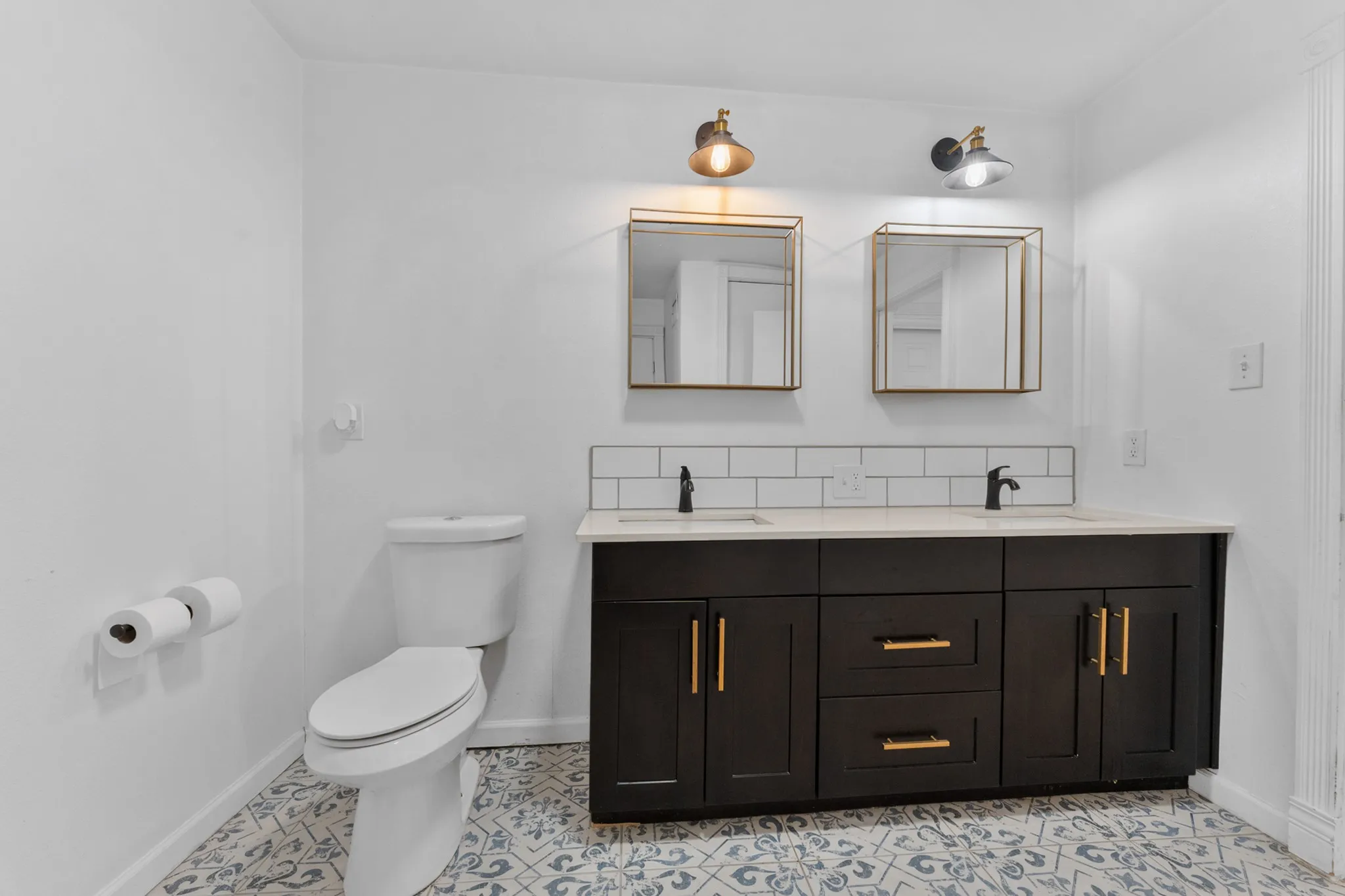 Dual vanity with matte black hardware, framed mirrors, and custom lighting