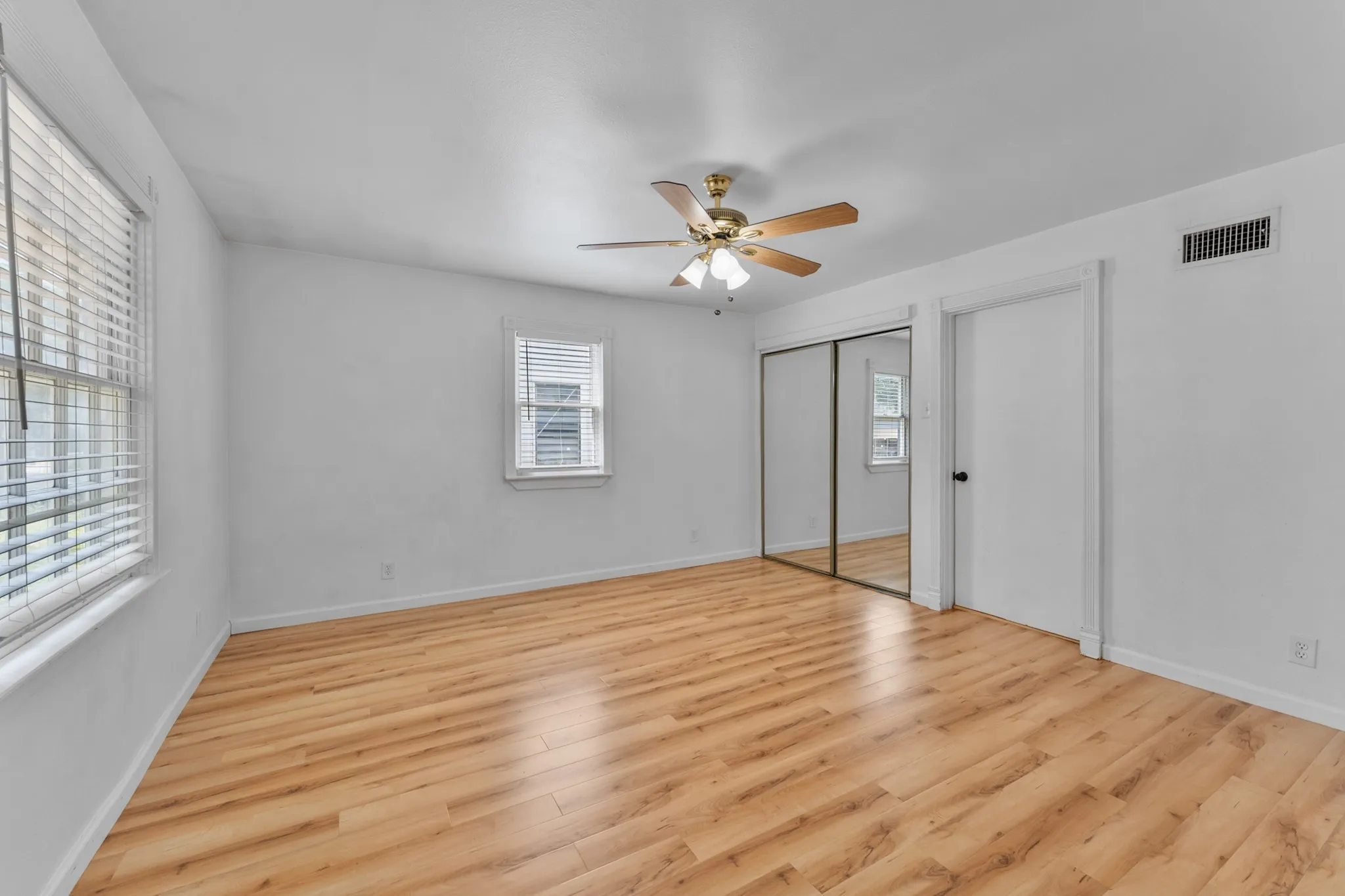 Wood-finish flooring with multiple windows and a ceiling fan