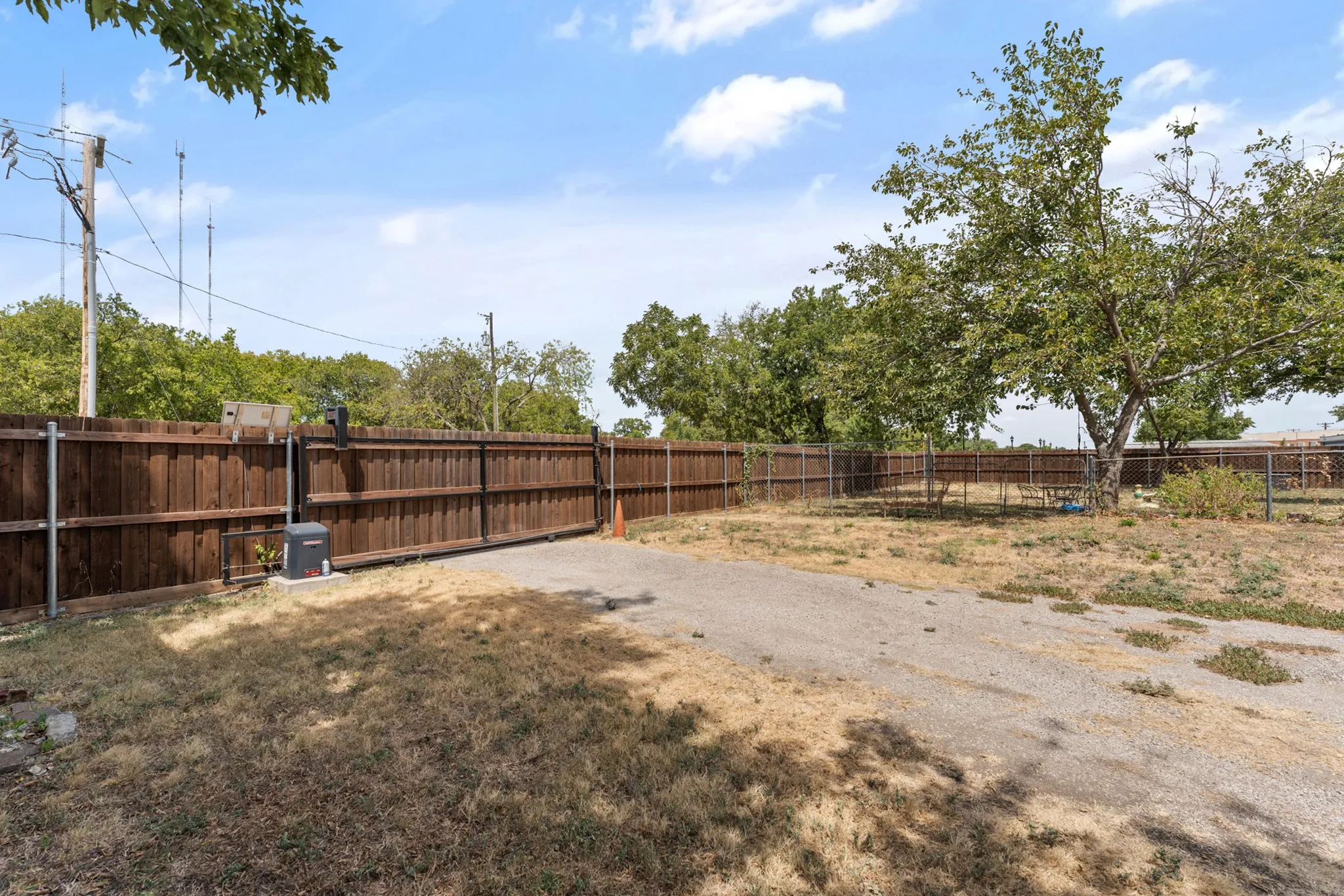 Private wood fence with an automated gate and a large tree