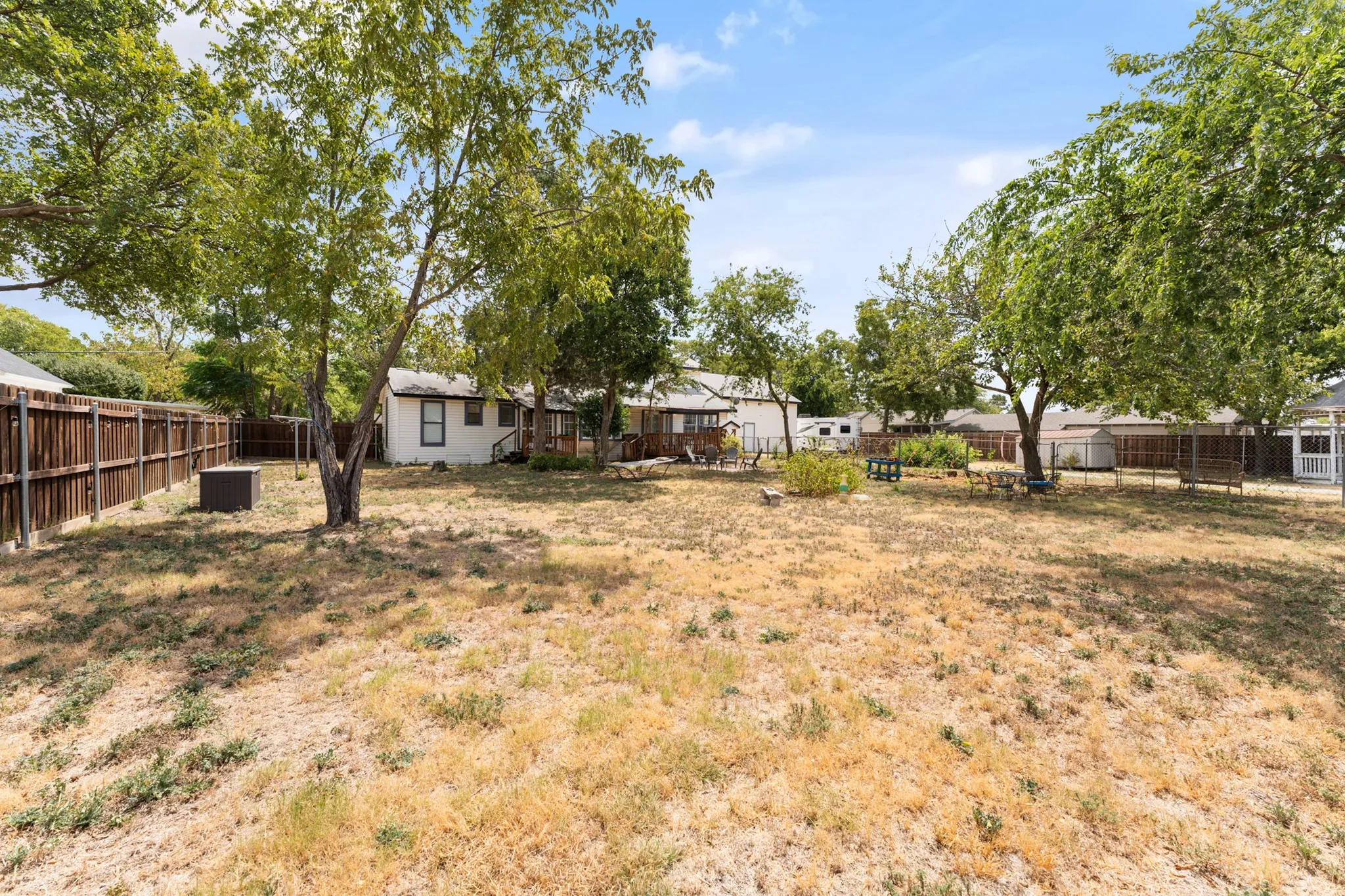Expansive backyard featuring mature trees and wood fencing