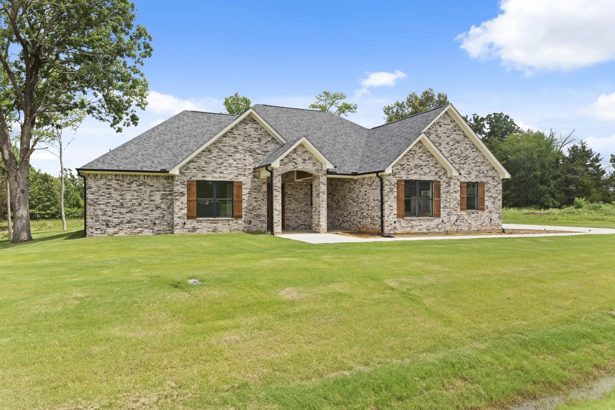 Brick exterior with a dark-pitched roof, gabled accents, and contrasting wood-finish shutters
