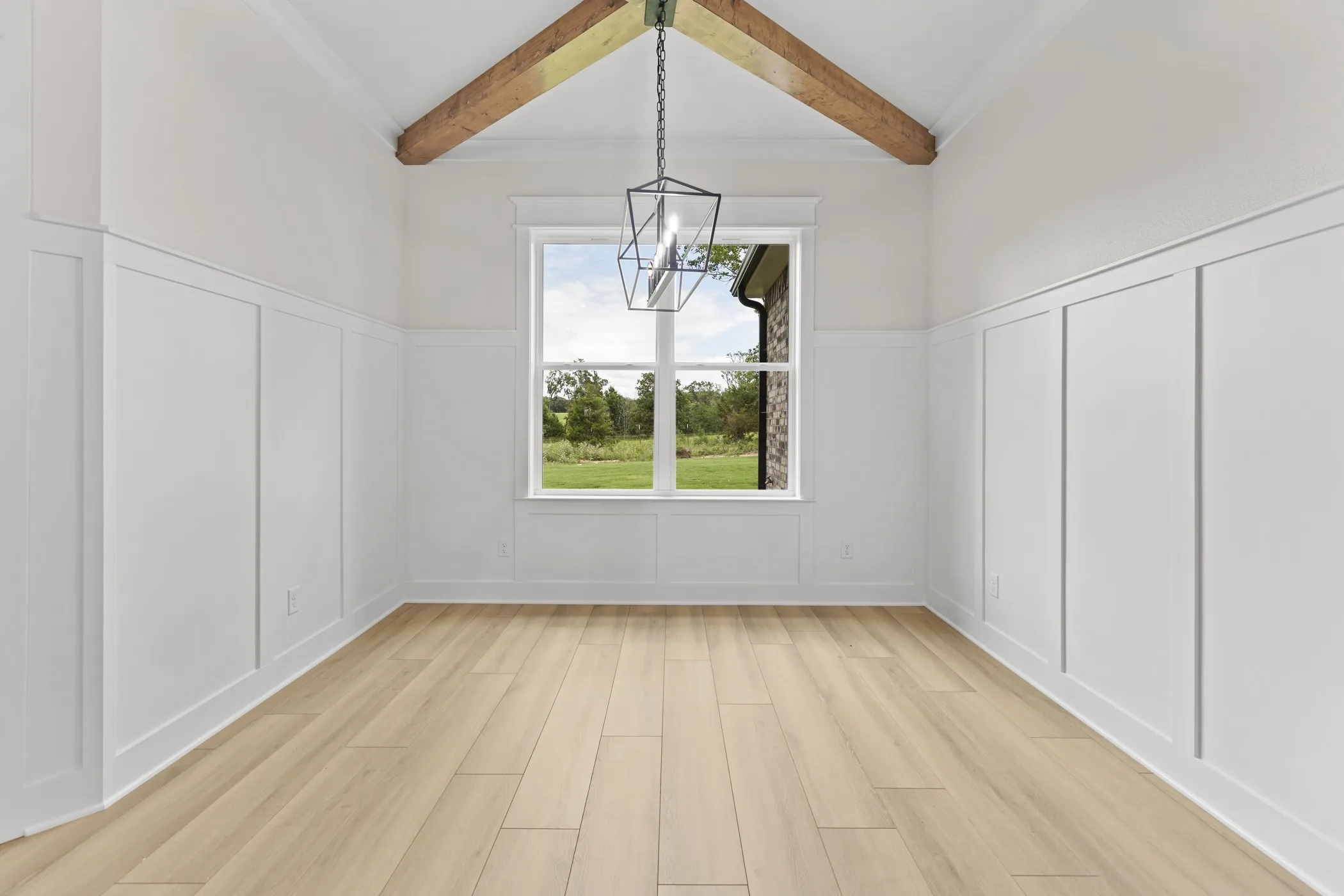 Vaulted ceiling with exposed wood beams, wood-finish flooring, paneled wainscoting, and a geometric pendant light fixture