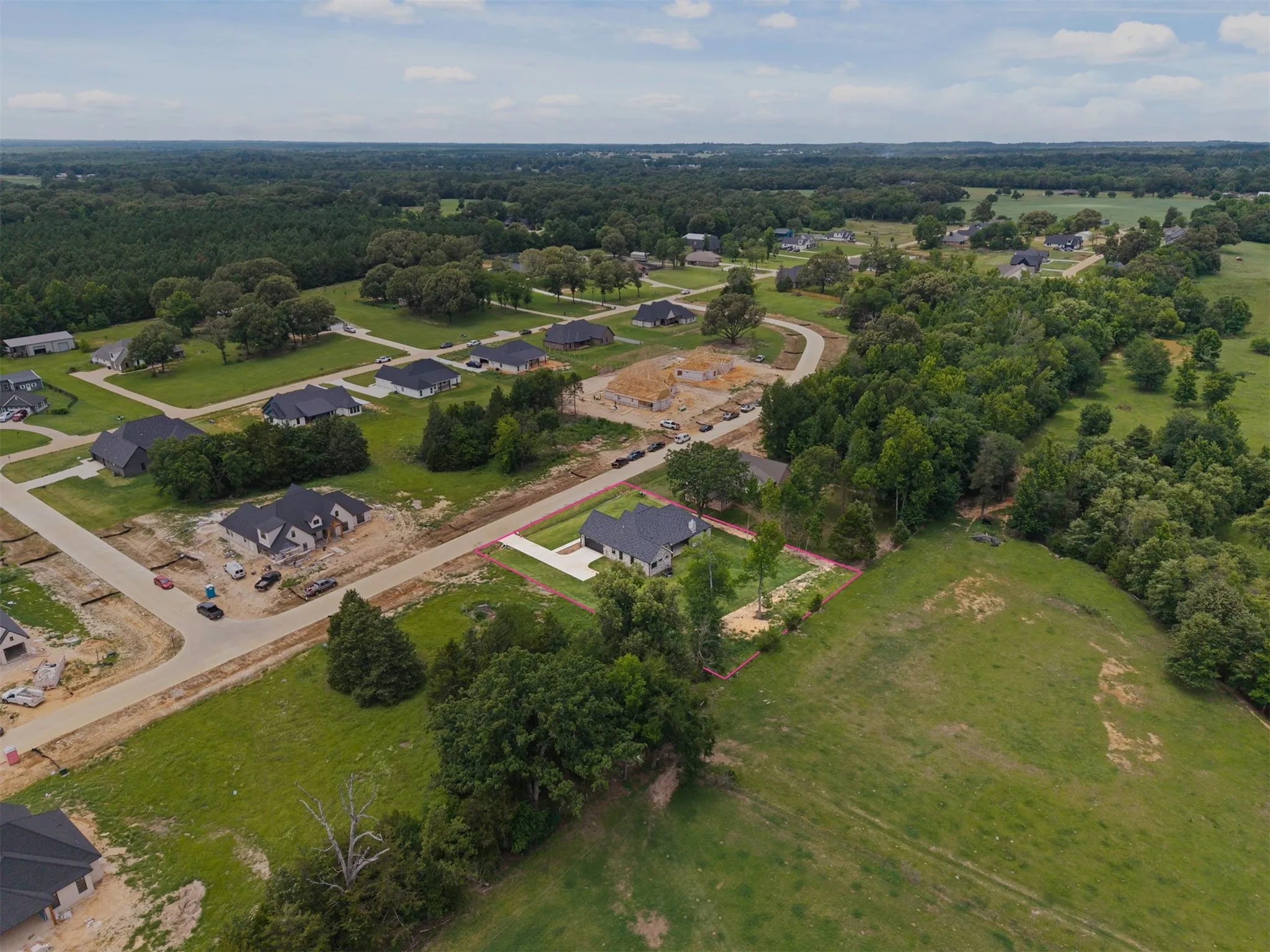 Aerial perspective showcasing residential development with paved streets, surrounded by expansive green spaces and mature trees
