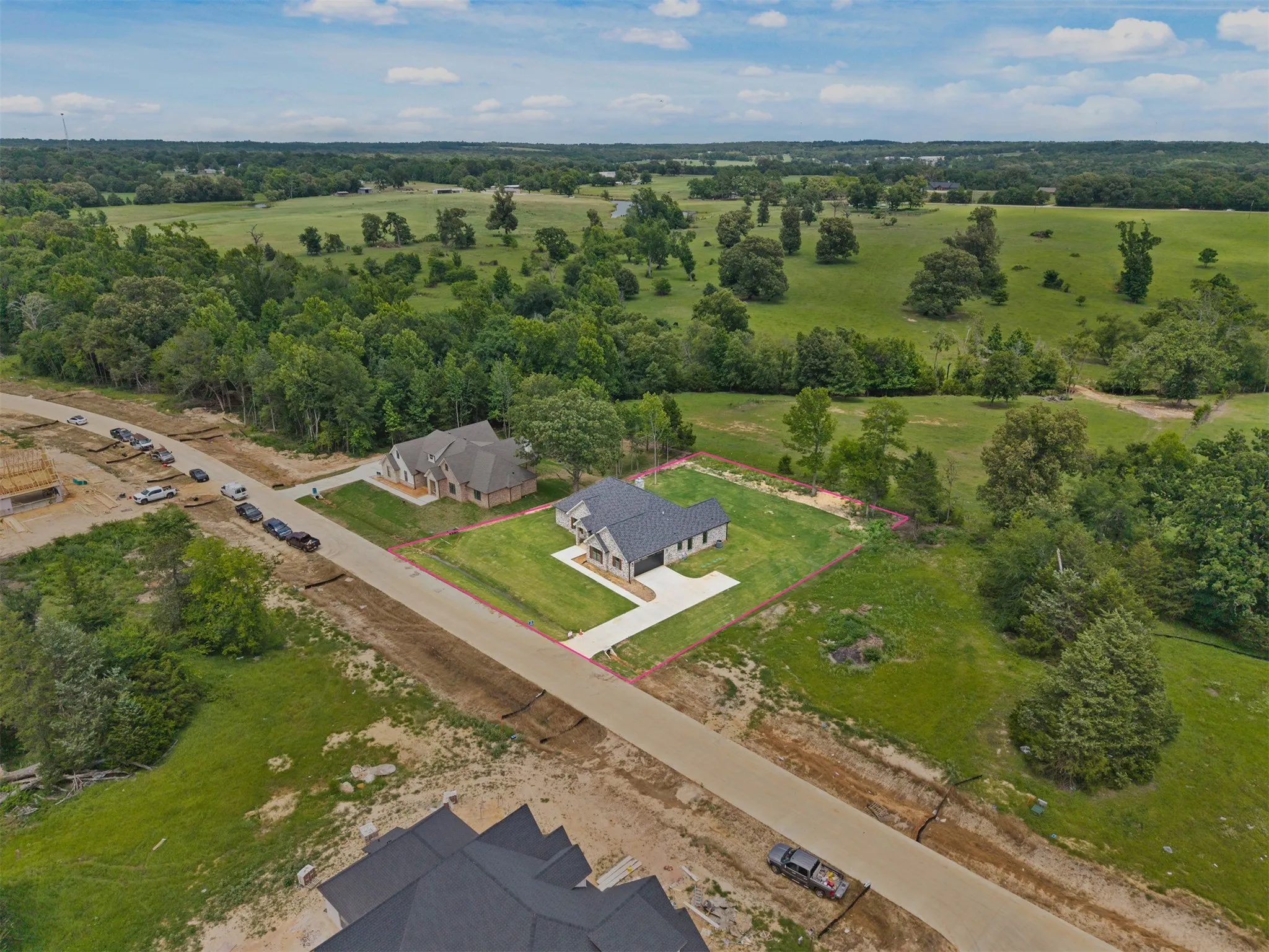 New construction residence featuring a dark gray roof, light-colored exterior, and an expansive green lawn
