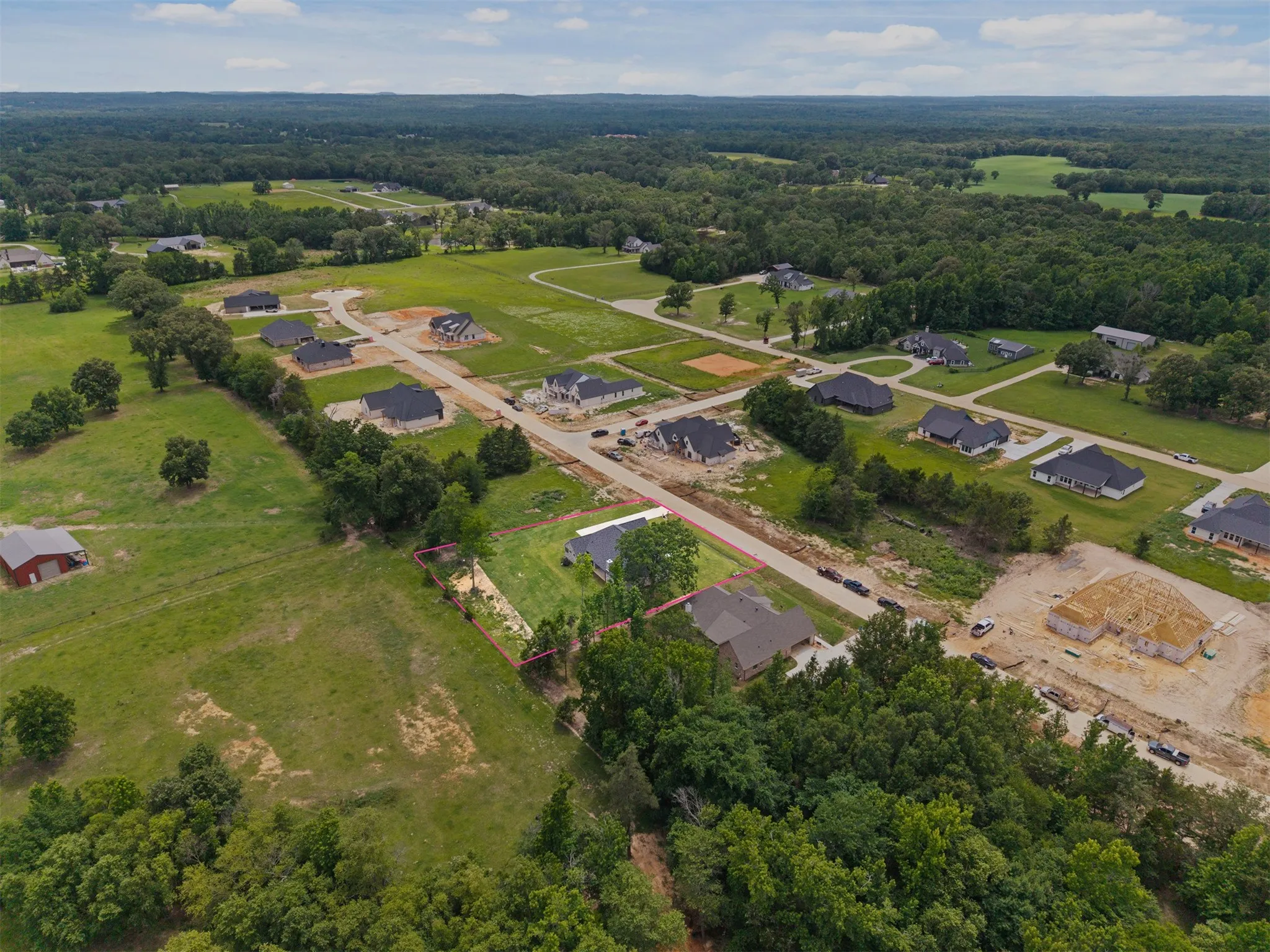 Expansive lot with partial tree coverage, surrounded by a developing neighborhood with established and under-construction residences