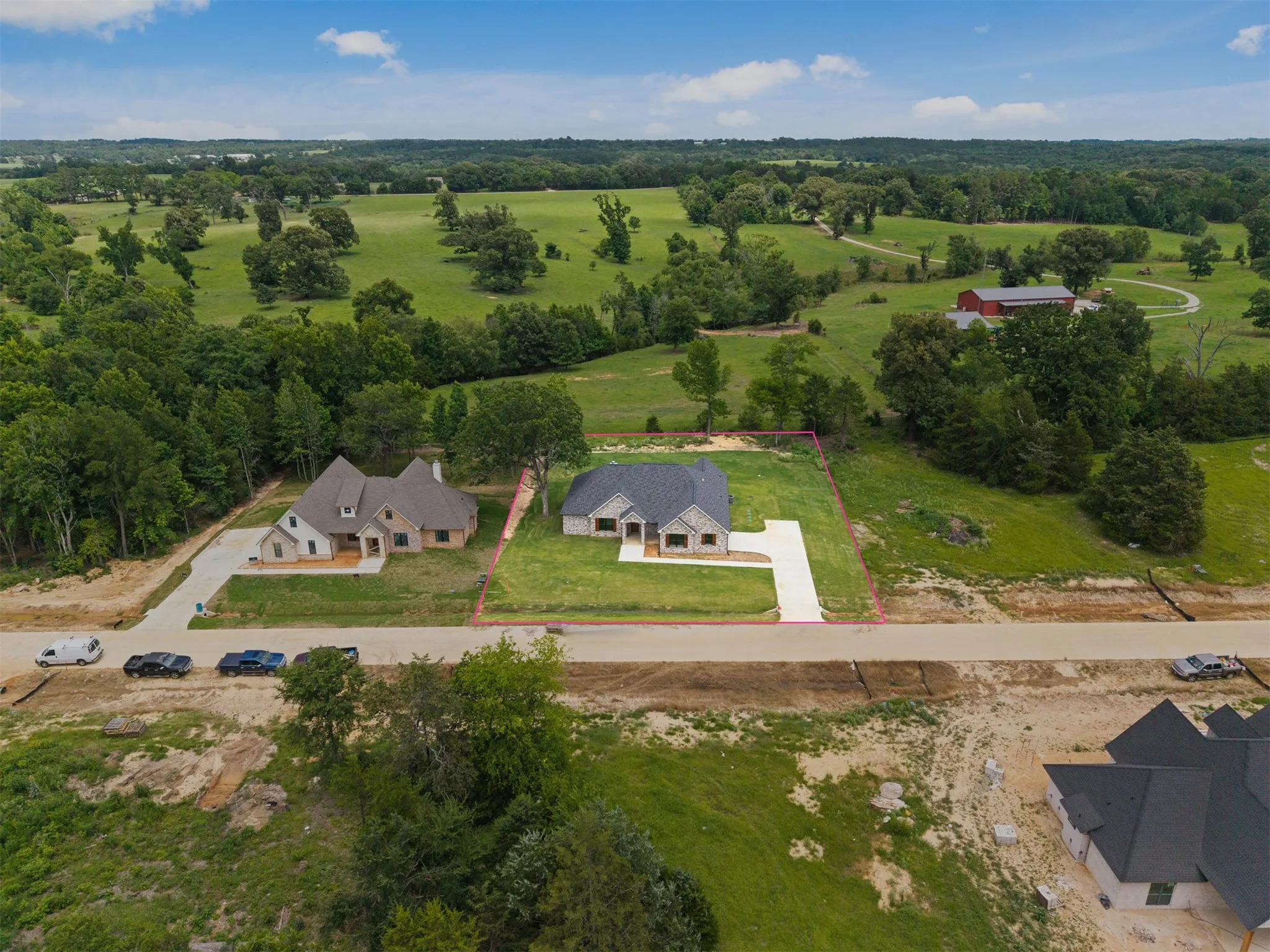 New construction residence featuring a light-toned brick exterior, a dark-toned roof, and a concrete driveway