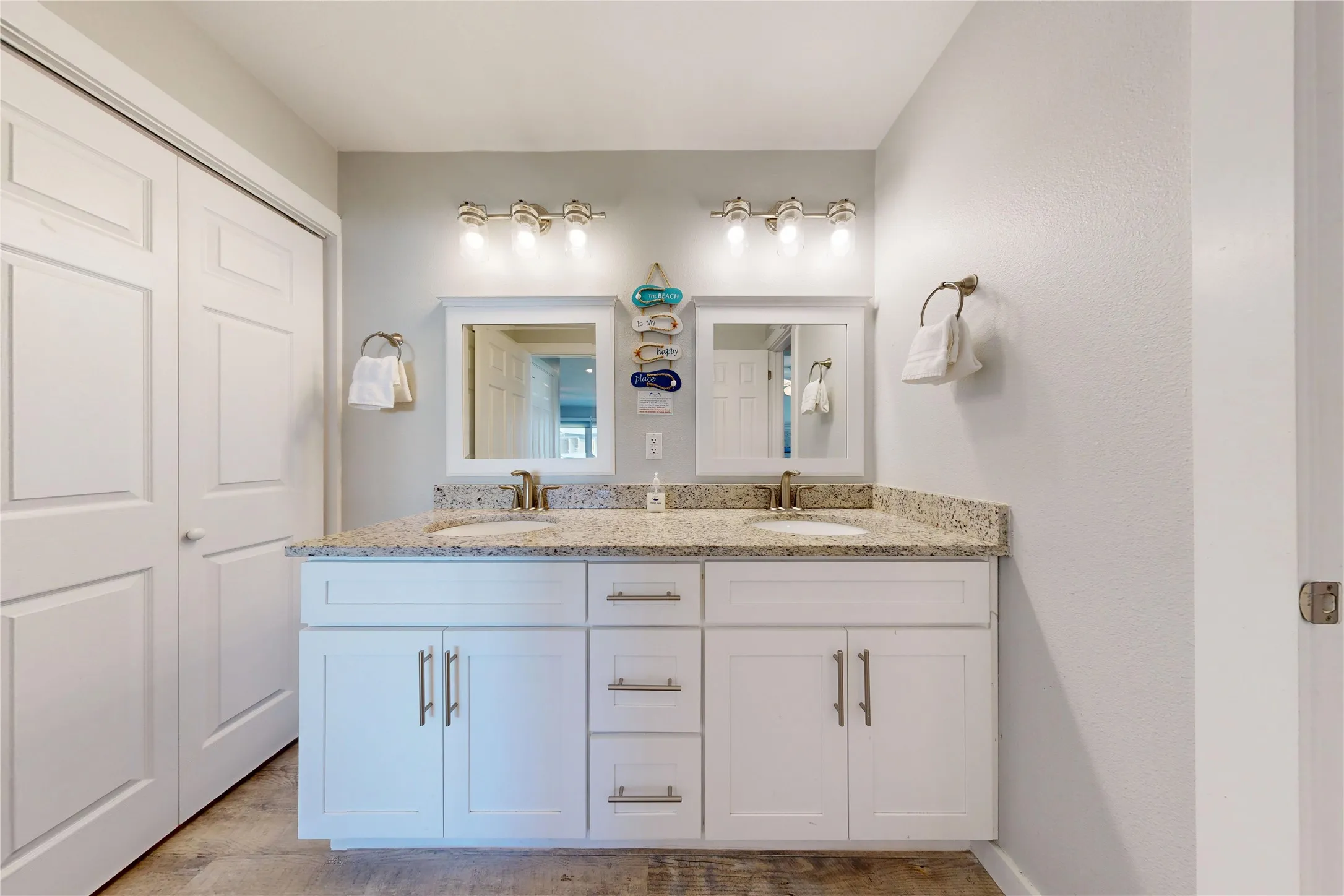 Dual vanities with granite countertops, white cabinetry, and undermount sinks