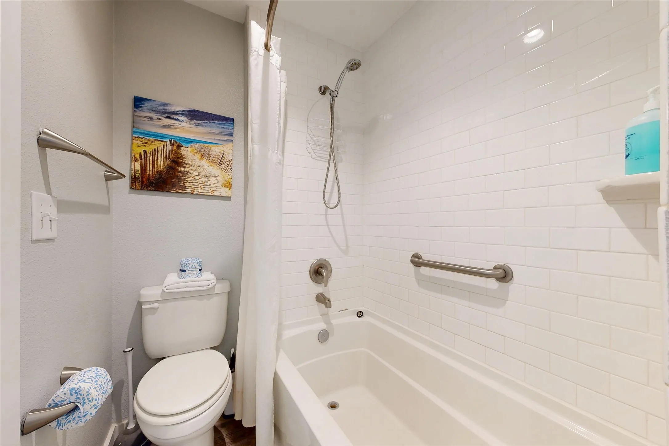 White subway tile surround, built-in bathtub, brushed nickel fixtures, wall-mounted shelving, and a toilet