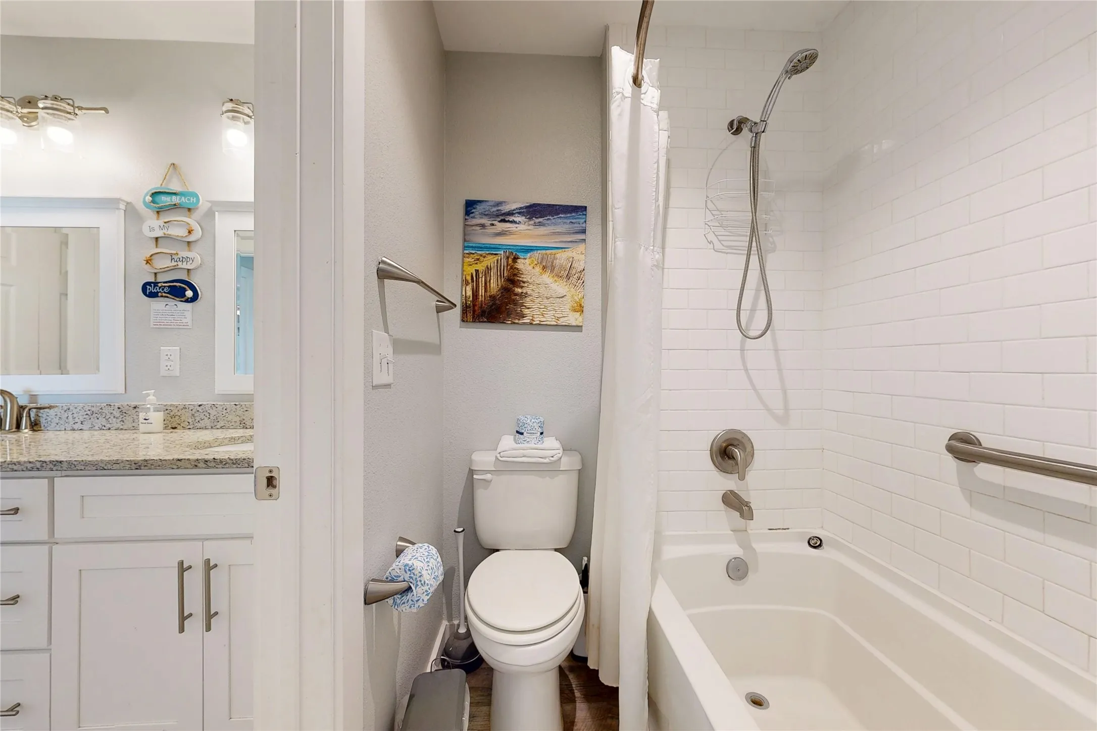 Bathtub with white subway tile surround, brushed nickel fixtures, and a shower grab bar