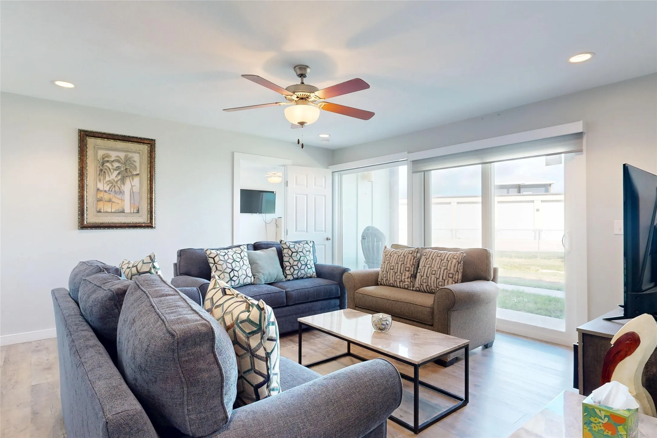 Recessed lighting, ceiling fan with integrated light, wood-finish flooring, and sliding glass doors