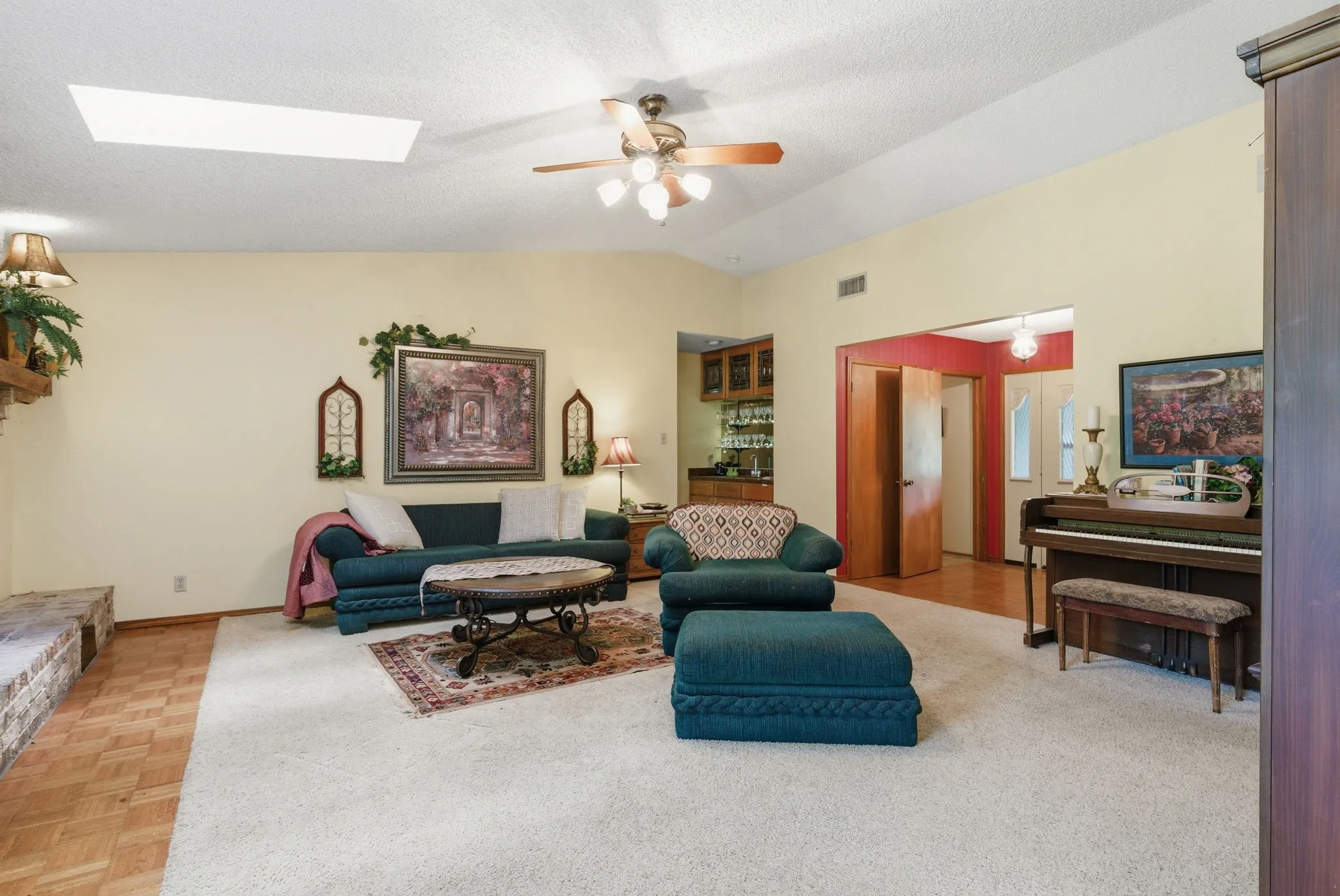 Vaulted ceiling with skylight and ceiling fan, built-in wet bar, and parquet wood flooring