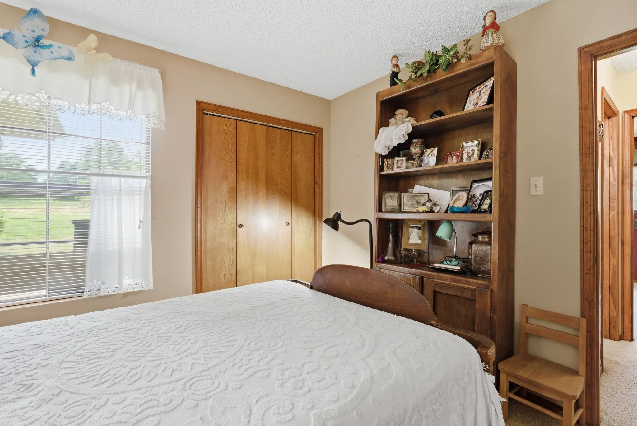 Double-pane window with blinds, wood-finish closet doors, and a built-in wood-finish bookcase