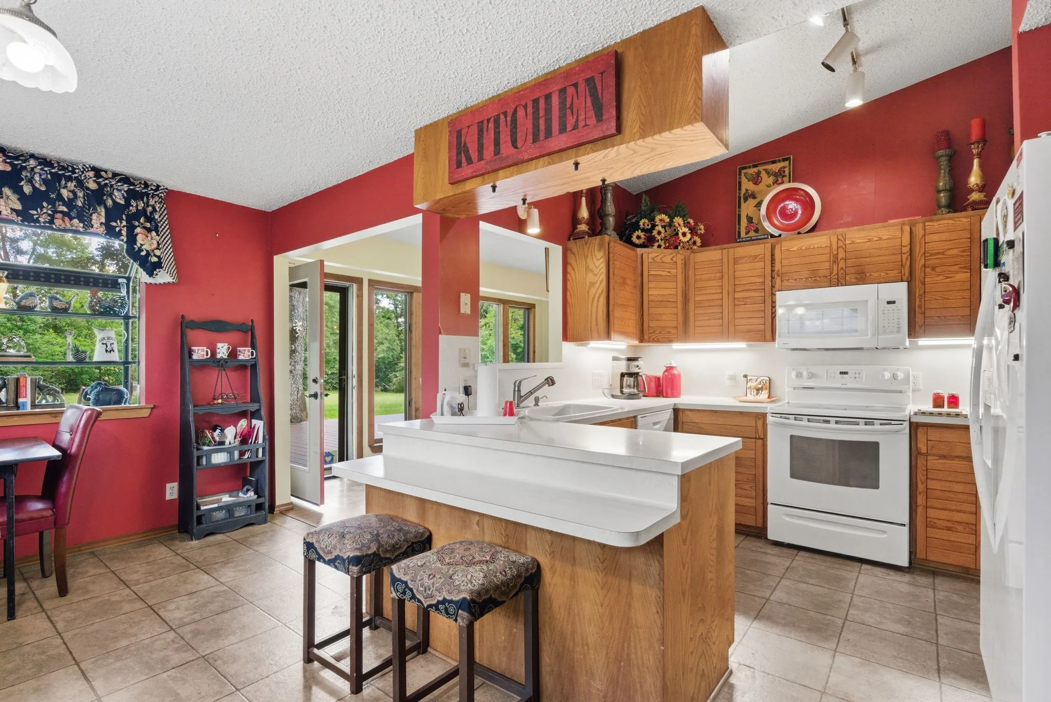 Kitchen featuring wood cabinetry, white appliances, a center island with bar seating, and tile flooring
