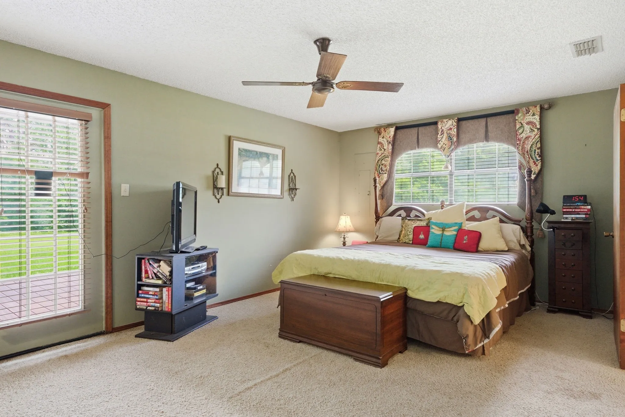 Ceiling fan with light fixture, carpeted flooring, direct access to outdoor patio space, and multiple windows with blinds