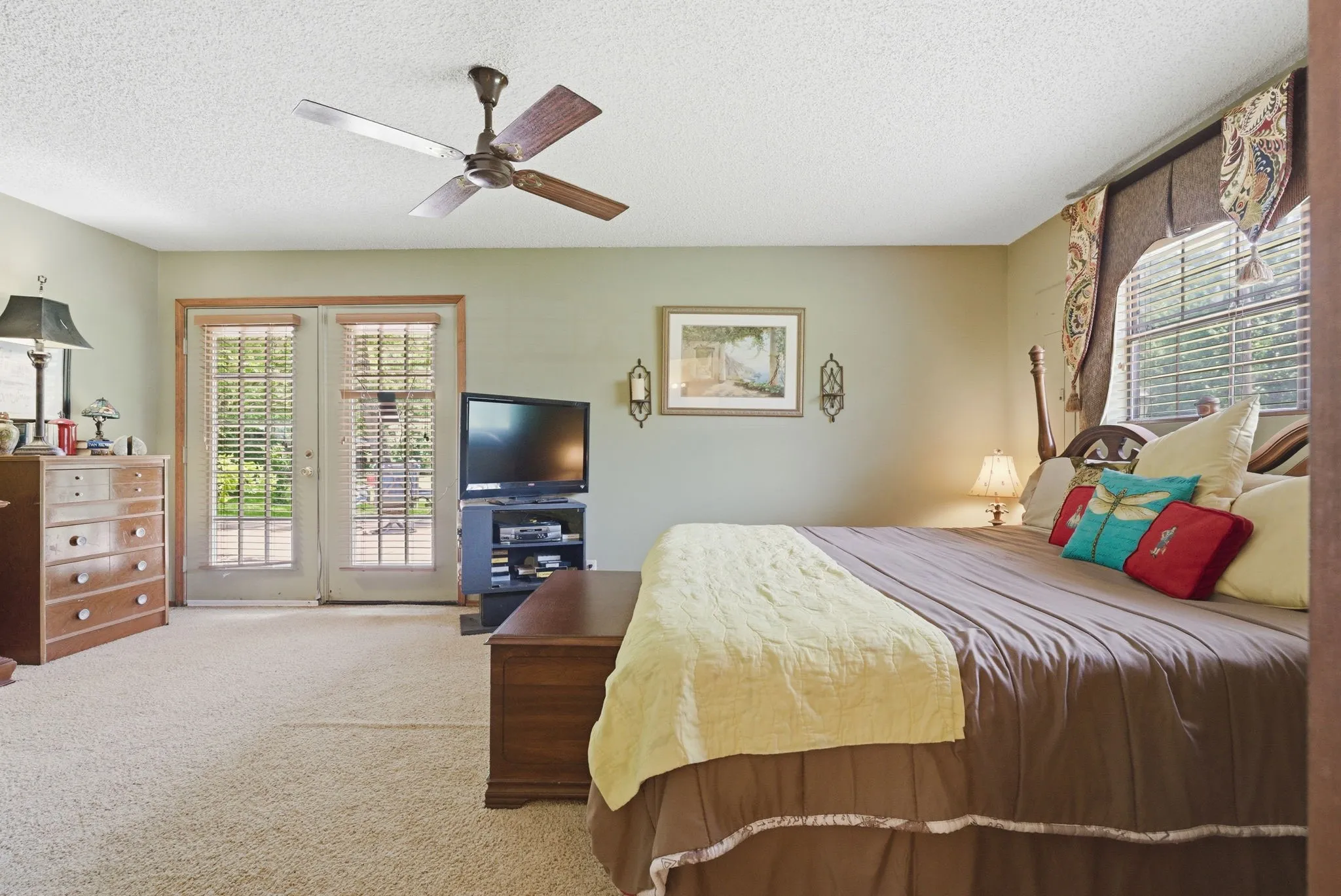 Ceiling fan, wall-to-wall carpeting, double French doors, large window with blinds, and neutral wall paint
