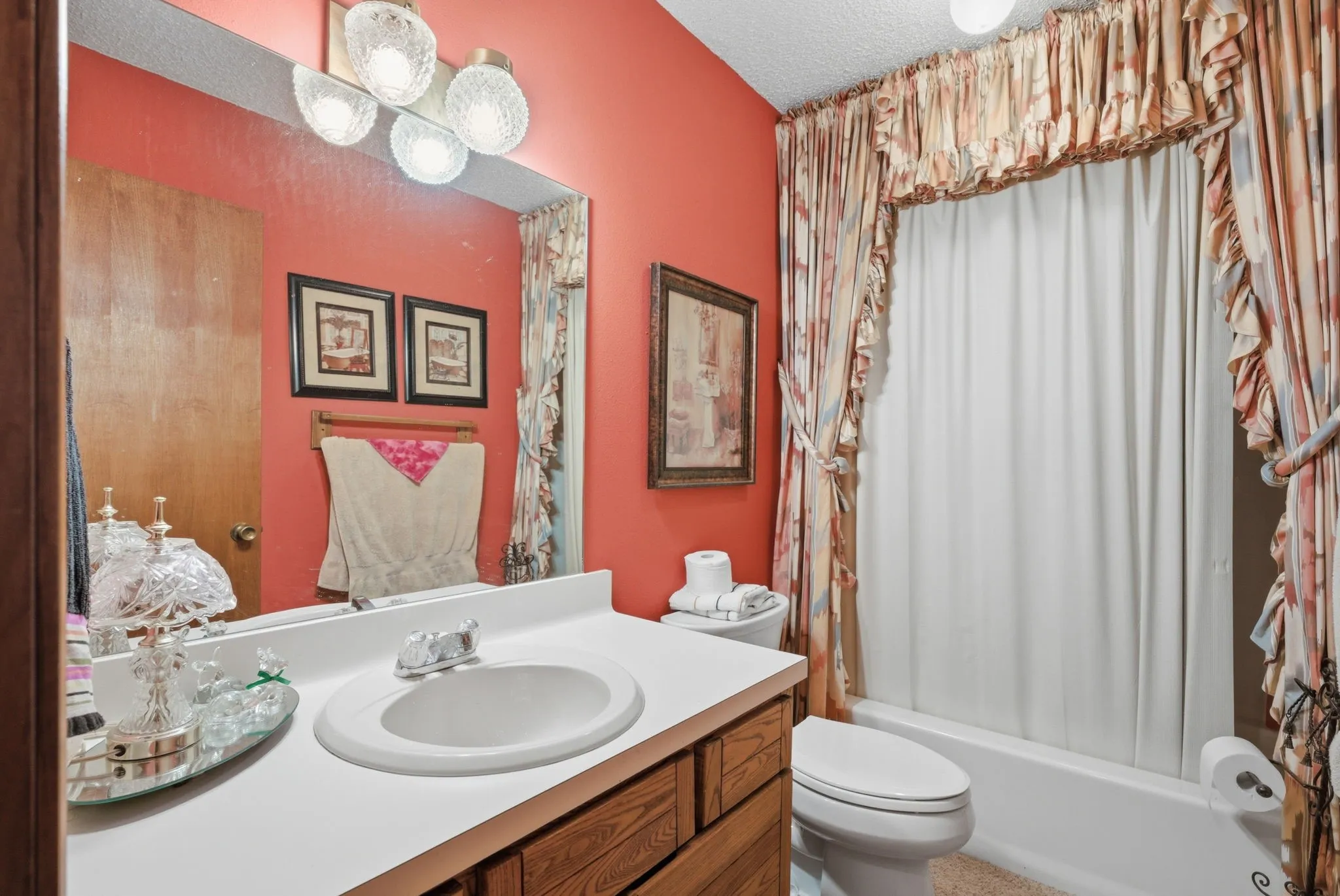 Integrated vanity with a single basin sink, wood-finish cabinetry, and a full-width mirror