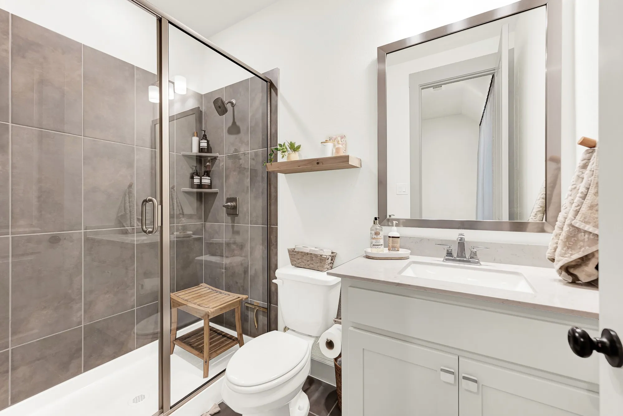 Sleek glass enclosures and rich floor-to-ceiling shower tiles create a modern design frame that catches bright, clean lighting. Visitors can wind down with a hot, spa-like rinse after a long day of travel, enjoying complete privacy and comfort.