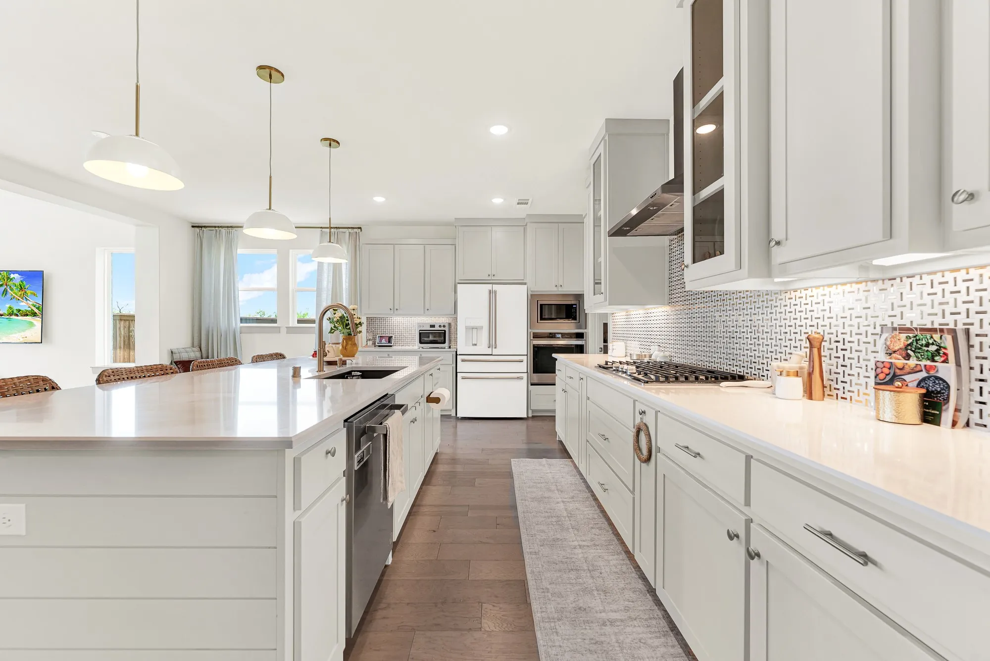 A polished geometric backsplash catches soft under-cabinet glow beside custom shaker cabinetry. It’s ideal for chatting over evening wine while pasta simmers nearby.