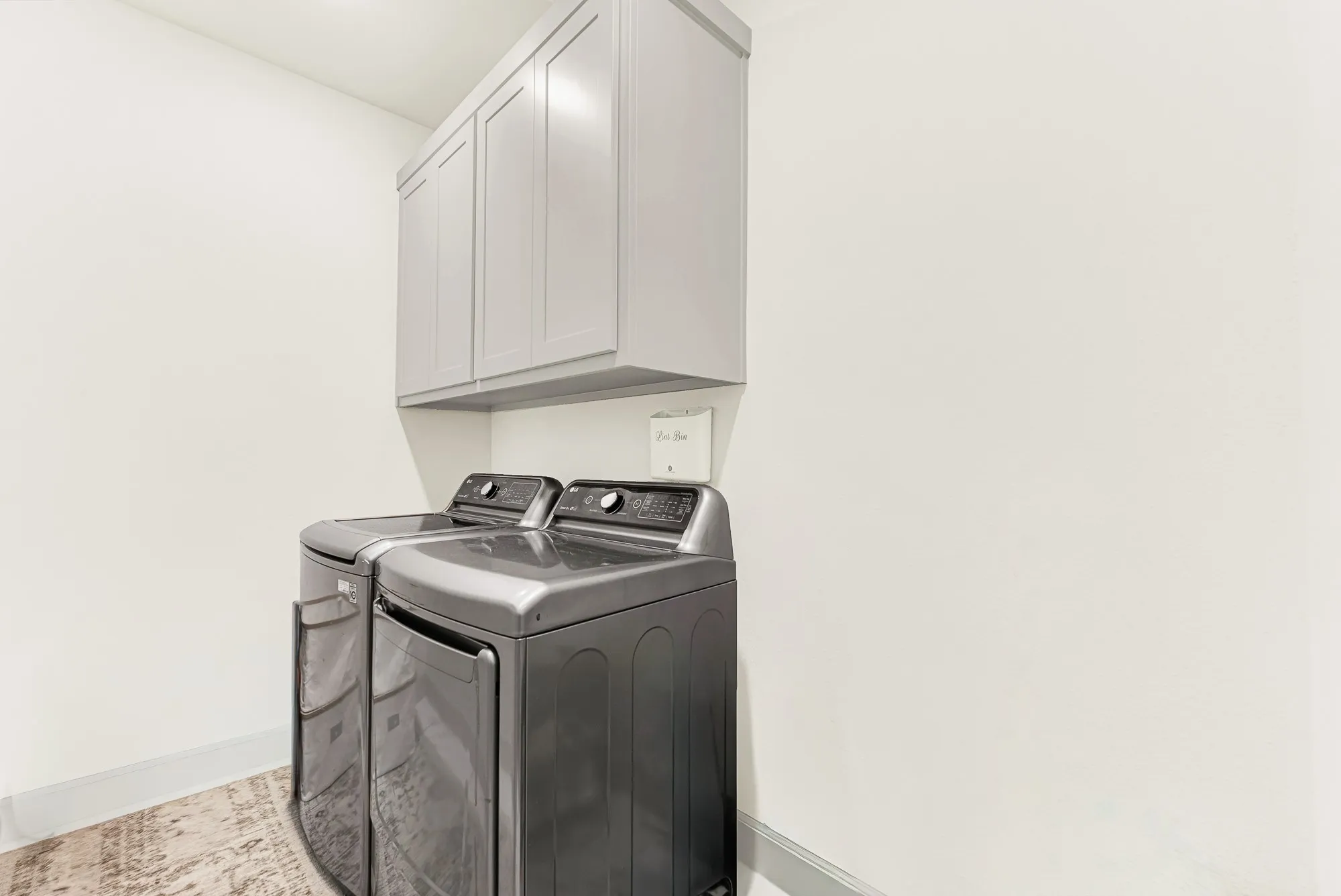 Mounted upper cabinetry floats neatly above bright, crisp walls to maximize vertical space and reflect surrounding light. You can easily stay on top of weekly family chores in a clean, hassle-free environment.