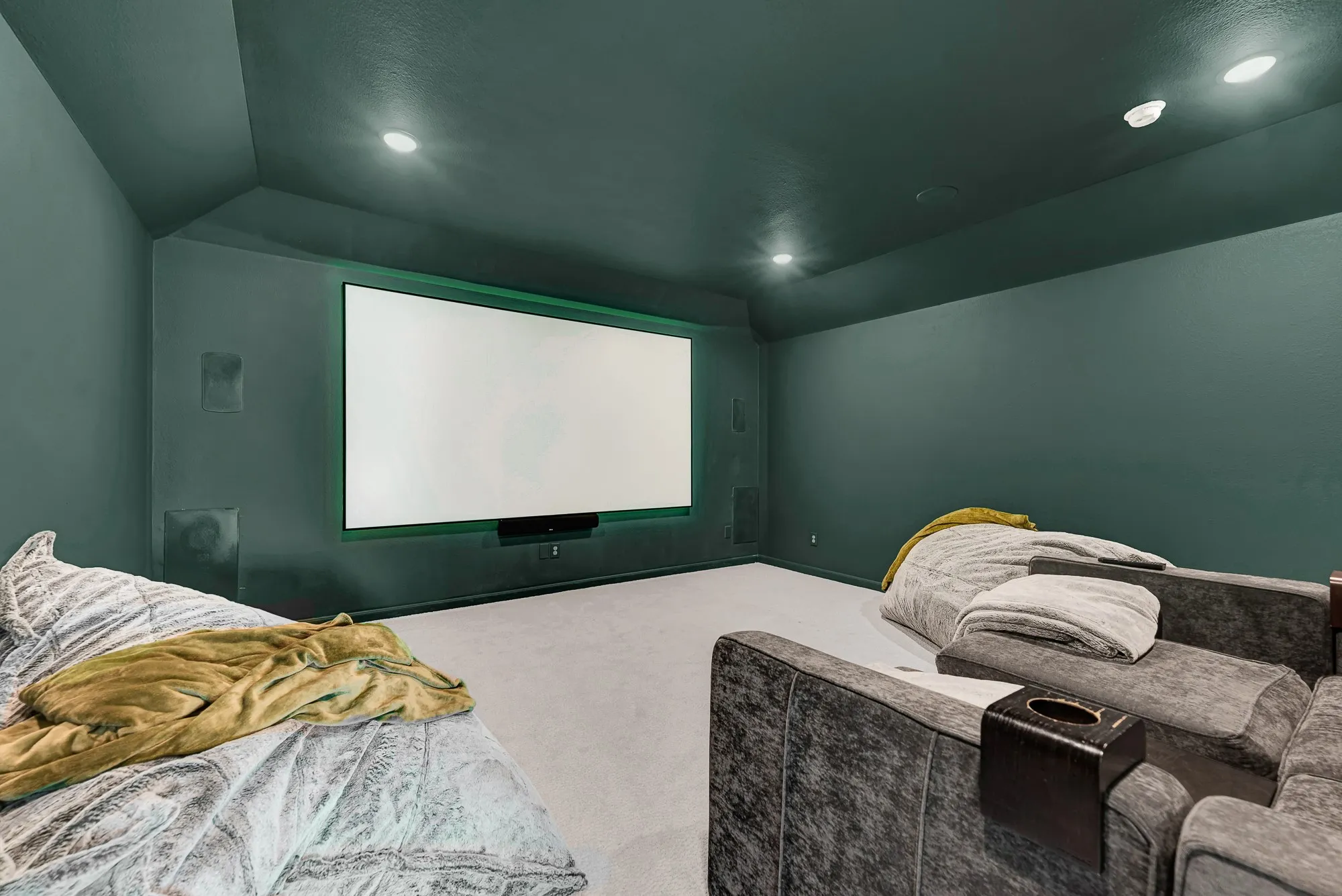 Deep moody walls and subtle backlighting surround a focal projection wall for a sleek cinema look. You can dim the overhead lights and immerse yourself in an epic Friday movie marathon with fresh popcorn.