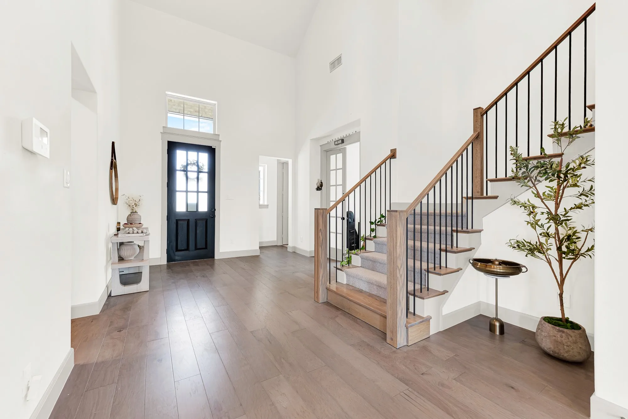 A grand, soaring ceiling pairs with a glass-paneled front door that floods the light wood floors with soft natural sunshine. It’s the perfect spot to kick off your shoes and welcome family home after a long day.