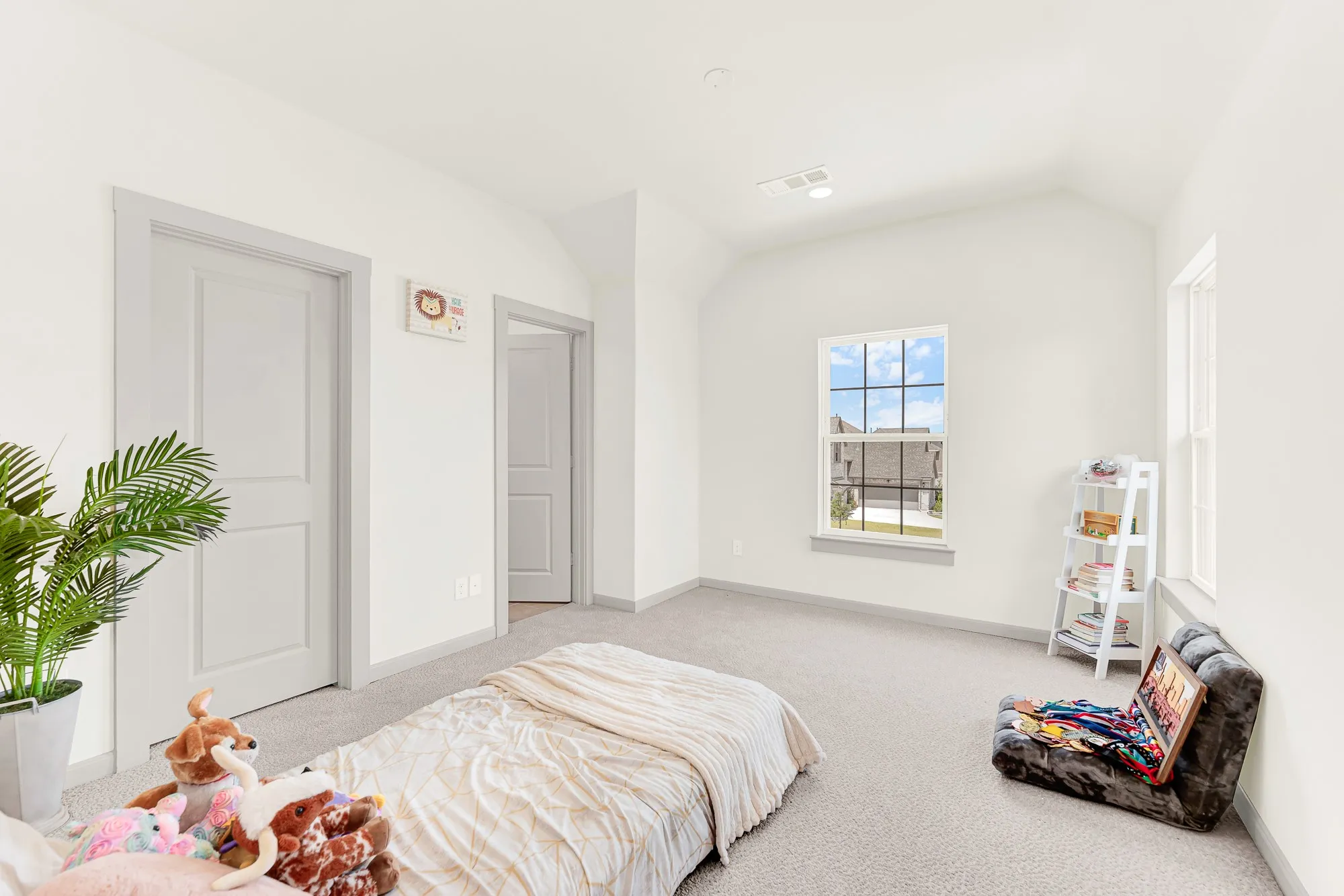 Dual-aspect windows frame neighborhood views while drawing balanced daylight across the geometric wall corners. Younger kids can spread out toys for imaginative floor play in their own cozy haven.