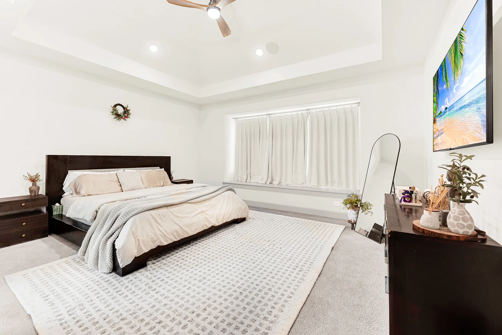 A tray ceiling adds vertical dimension over a wide window niche that filters soft ambient light. It’s a peaceful haven to unwind with late-night television after a busy afternoon
