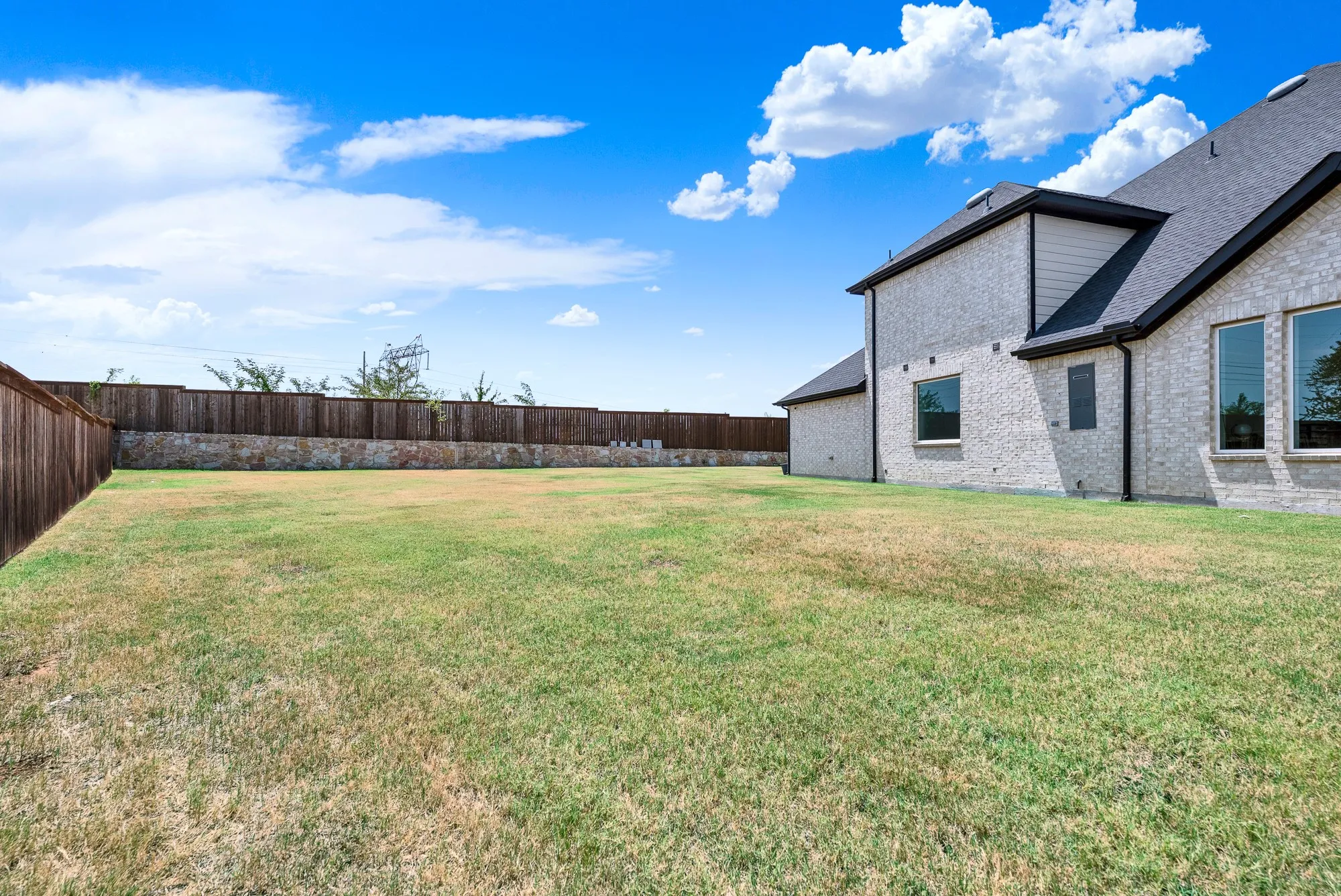 Sweeping rooflines and light brick walls stretch across an impressively wide, flat green expanse. It offers the ideal canvas for hosting lively weekend barbecues with plenty of space for everyone.