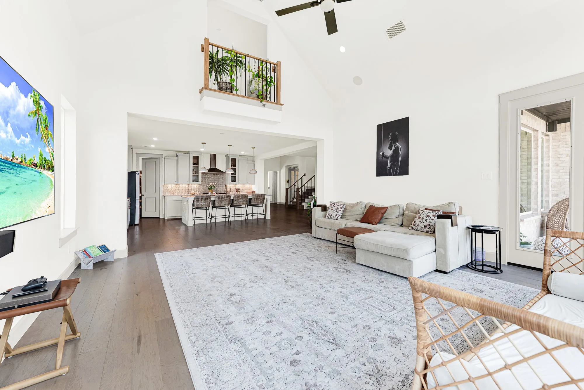 An interior balcony looks down over the airy layout, connecting the upper level to the primary gathering space. Picture hosting friends for game night with seamless access to snacks in the kitchen nearby.