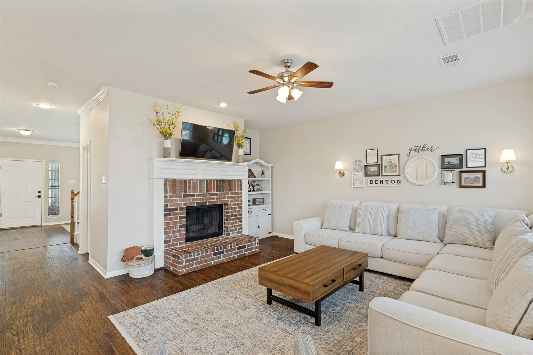 Brick fireplace with a wood mantel, built-in shelving, wood-finish flooring, recessed lighting, and a ceiling fan