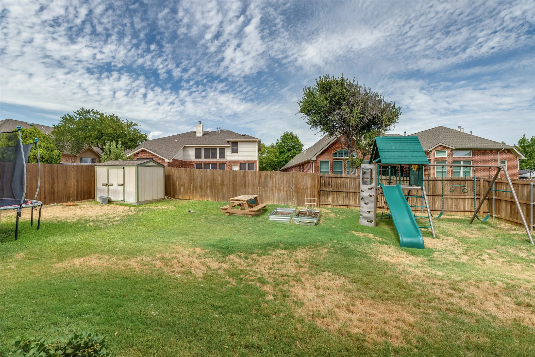 Fenced backyard with a storage shed, wood fence, and raised garden beds