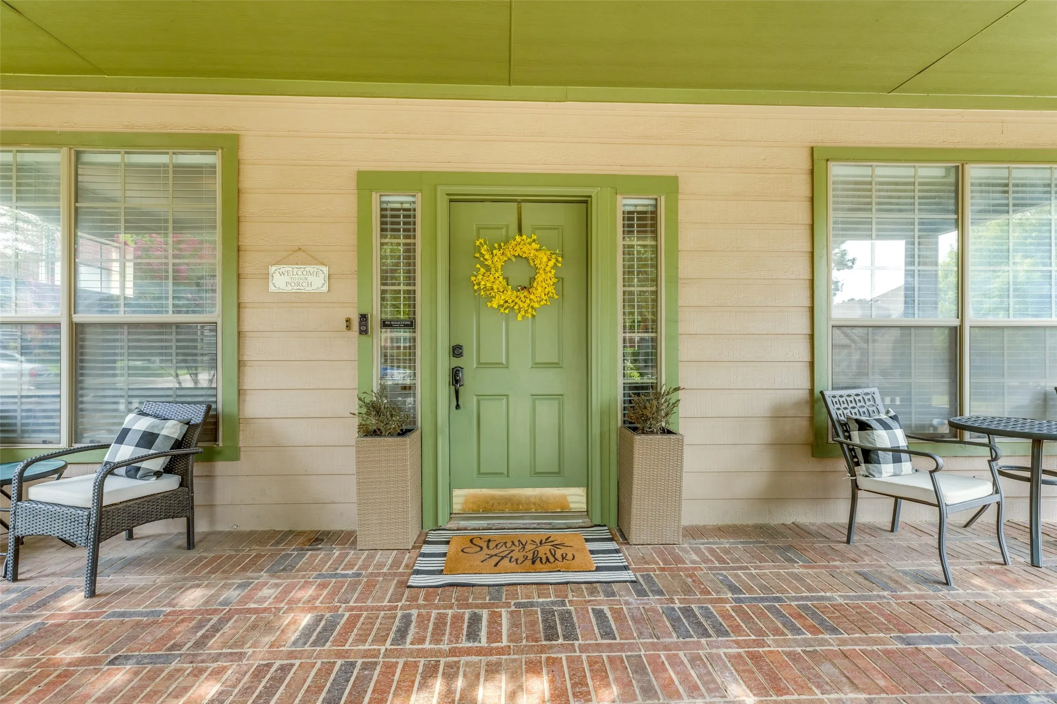 Front porch with brick-patterned flooring, horizontal siding, and a paneled entry door