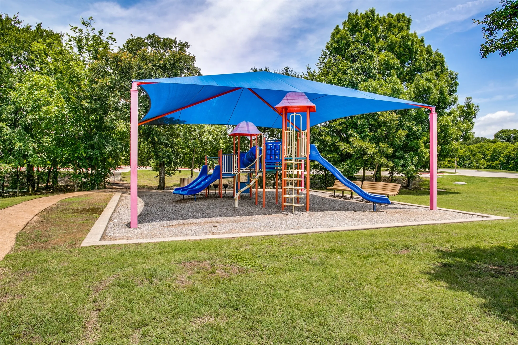 Recreational playground area featuring a shade structure, multiple slides, and a pea gravel base