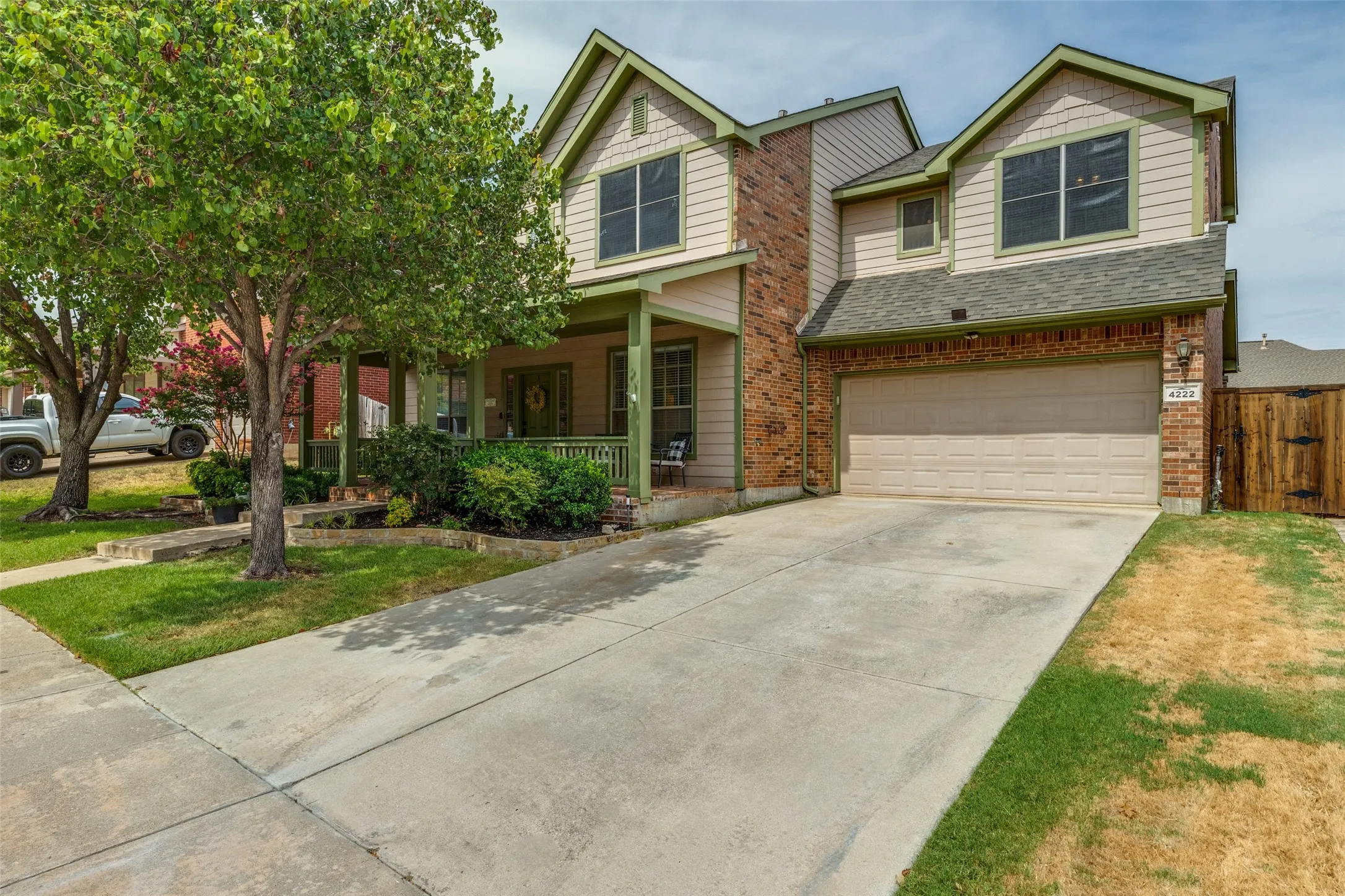 Two-story residence featuring a brick and siding exterior, covered front porch, attached garage, and a gated side yard