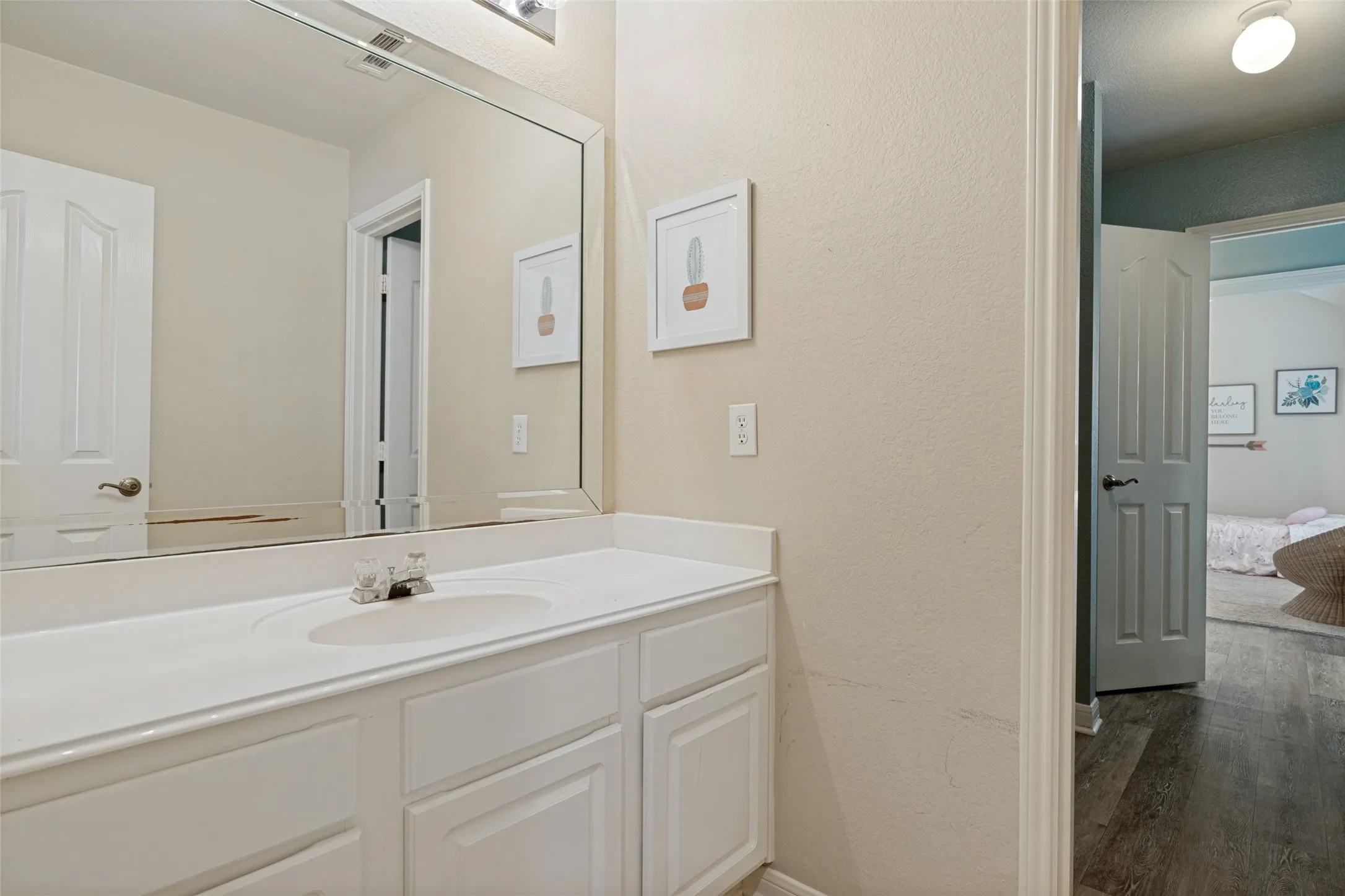 Vanity with an integrated sink, polished chrome faucet, and expansive mirror