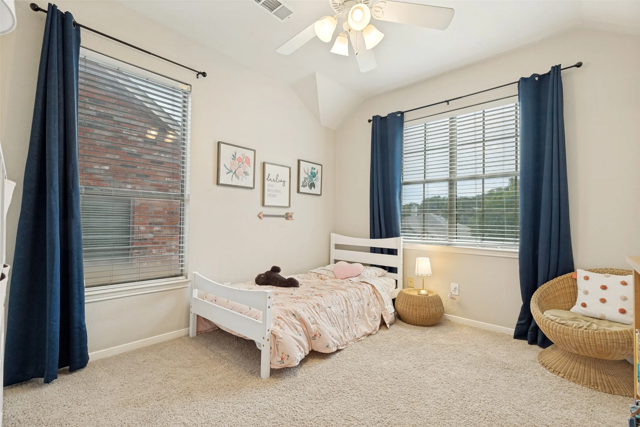 Carpeted room with a vaulted ceiling, ceiling fan, and two large windows