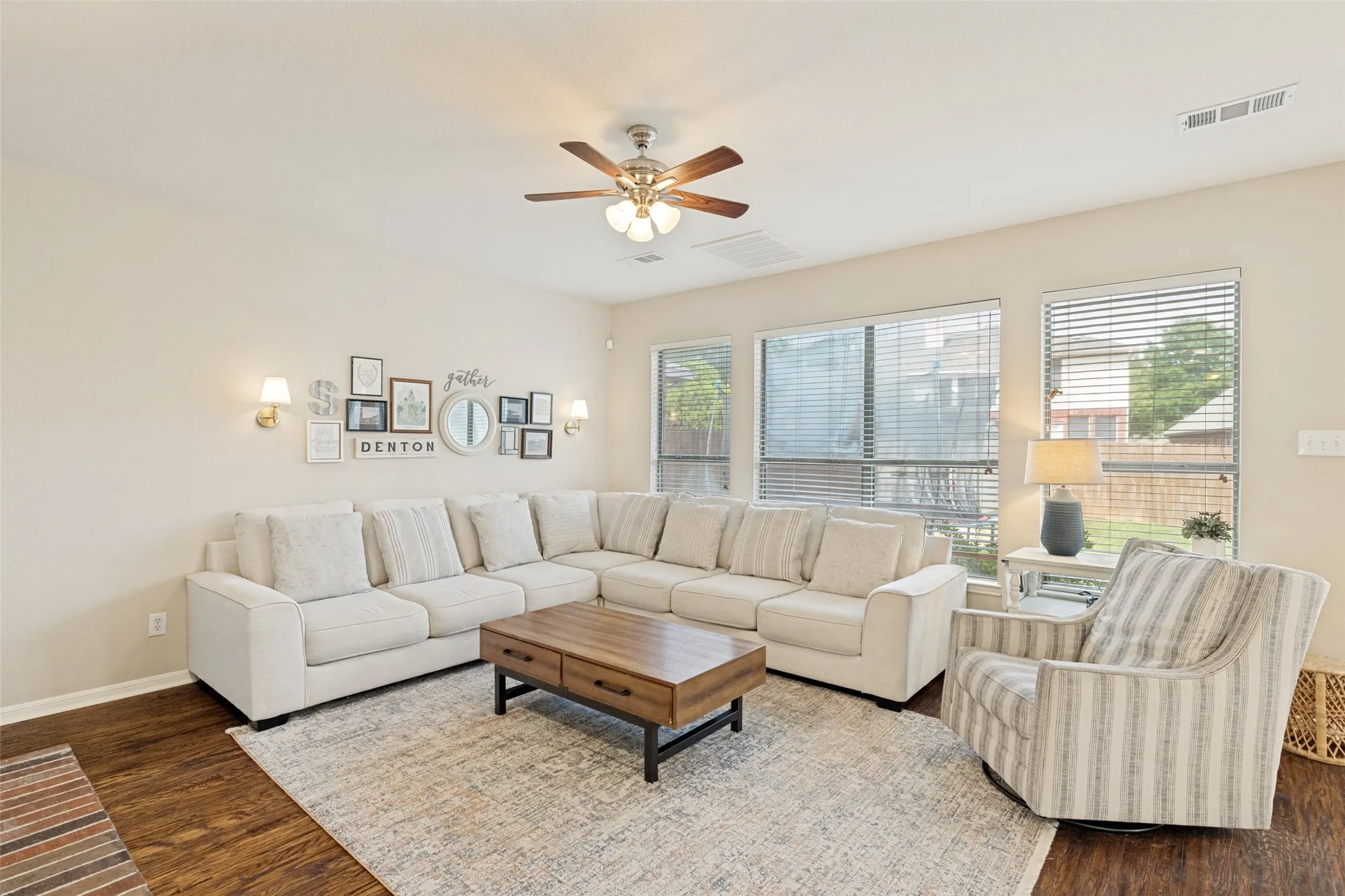 Recessed lighting, wood-finish flooring, ceiling fan with light fixture, multiple windows, and wall sconces