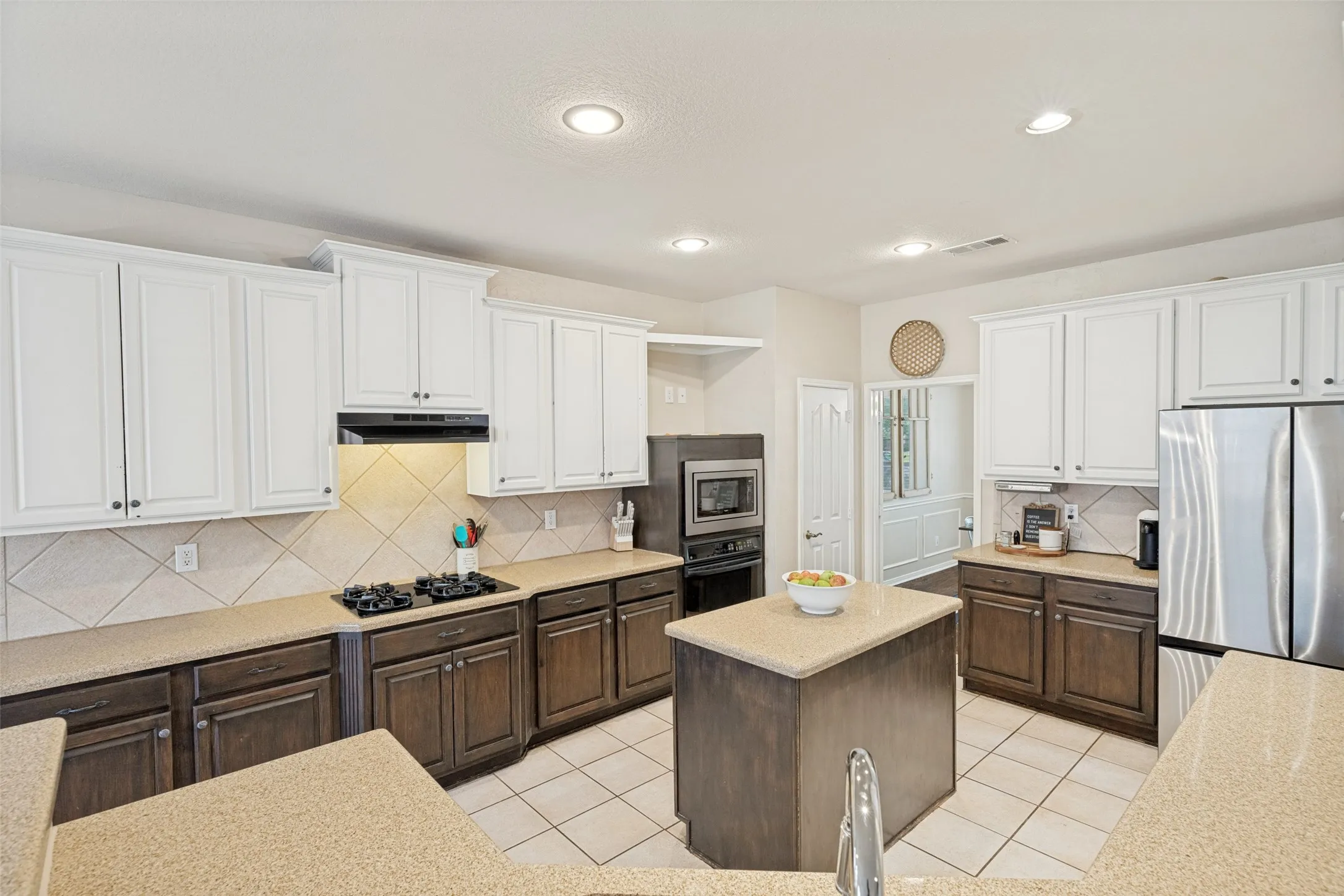 Kitchen featuring two-tone cabinetry, a central island, a built-in oven, a cooktop, and a tile backsplash