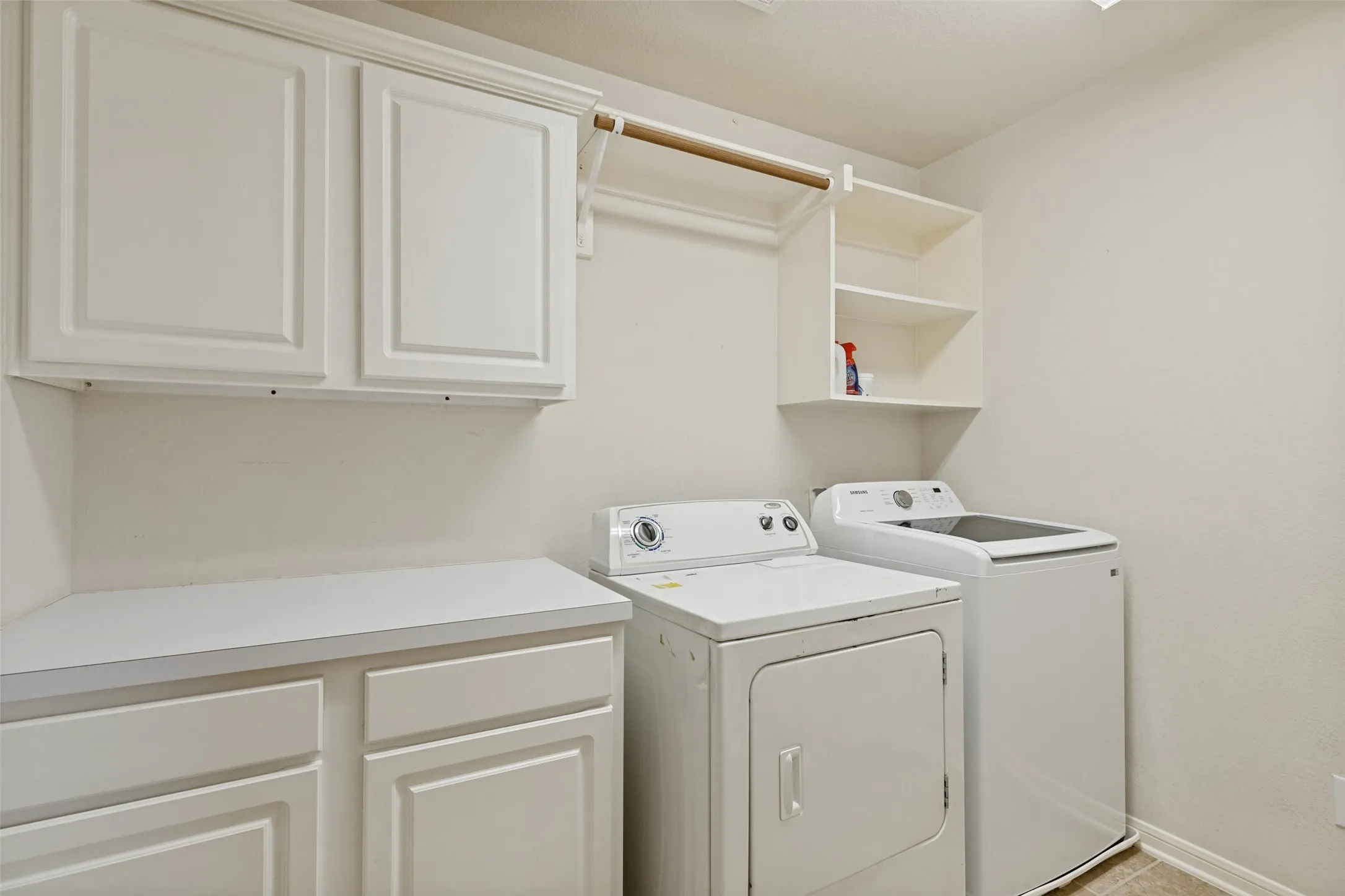 White shaker-style cabinetry, integrated hanging rod, built-in shelving, and countertop space