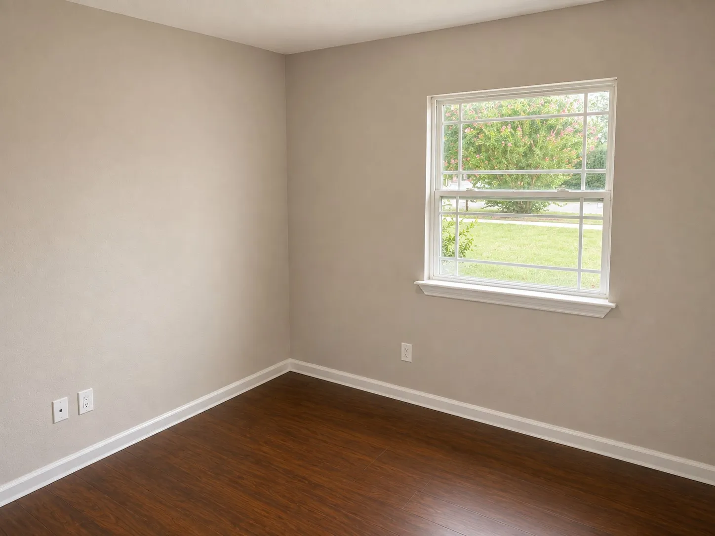 Wood-finish flooring, neutral wall tones, and a white-framed window with grilles