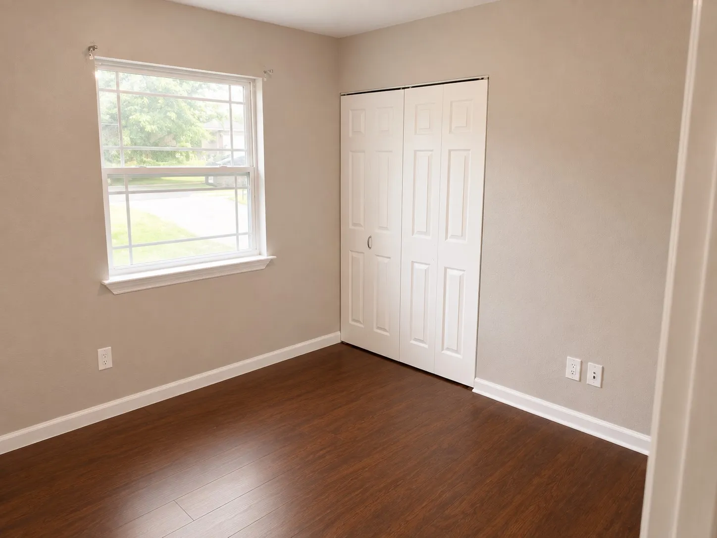 Wood-finish flooring, neutral wall tones, white trim, and a window with a grid pattern