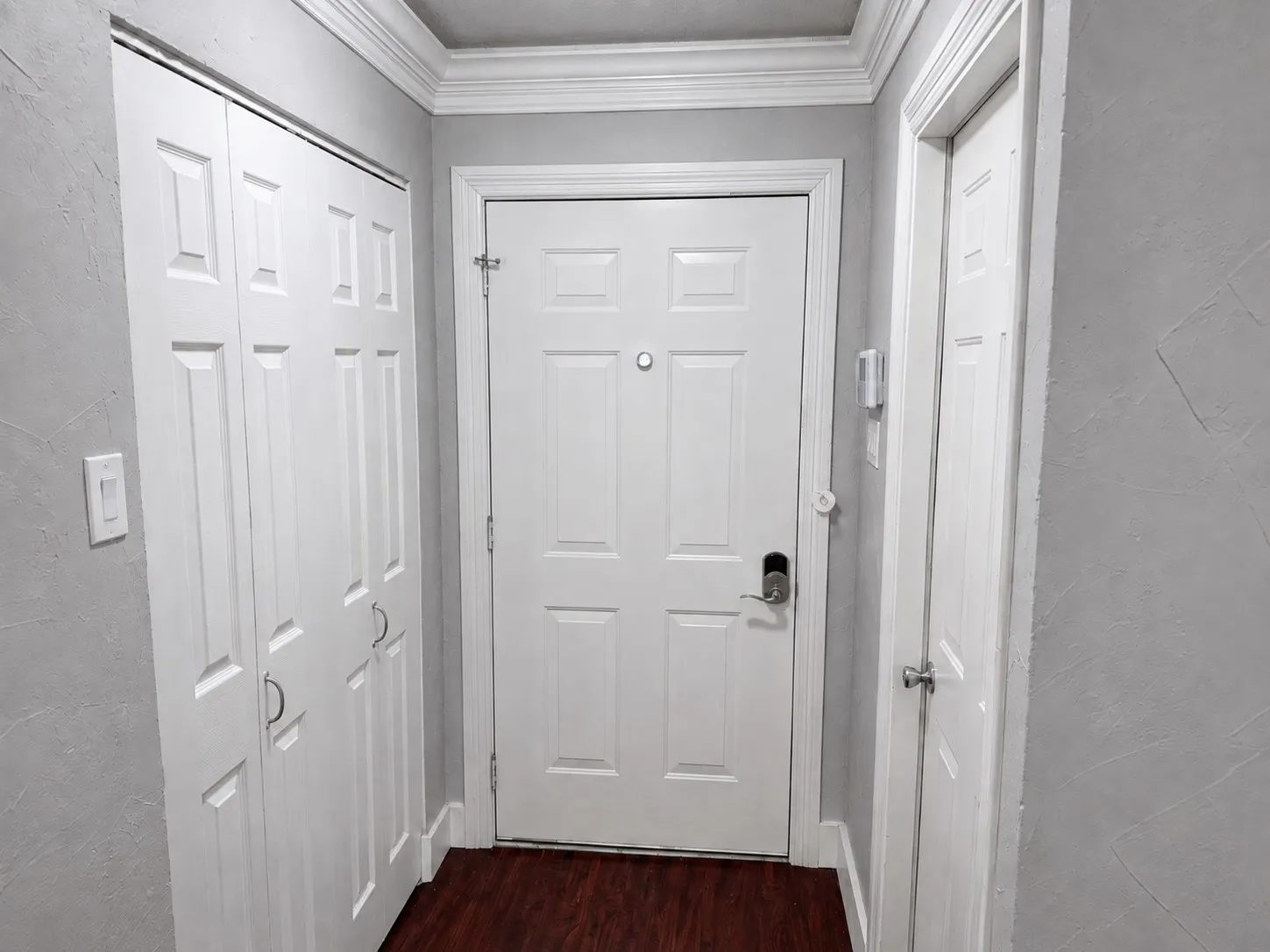 Wood-finish flooring with white trim and crown molding