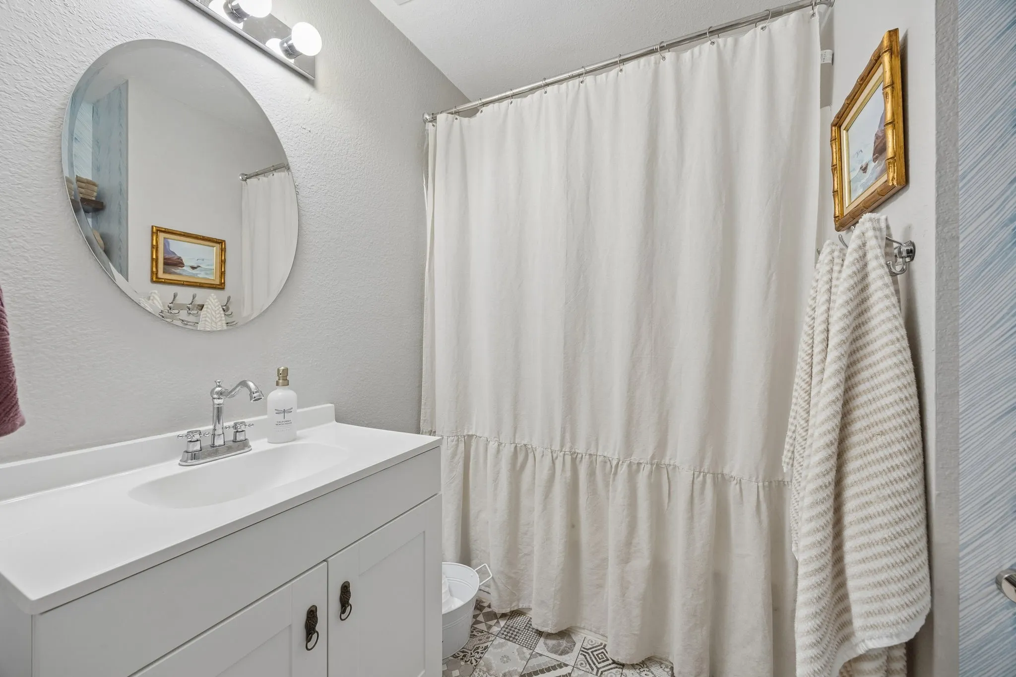 White vanity with integrated sink, chrome faucet, and overhead lighting