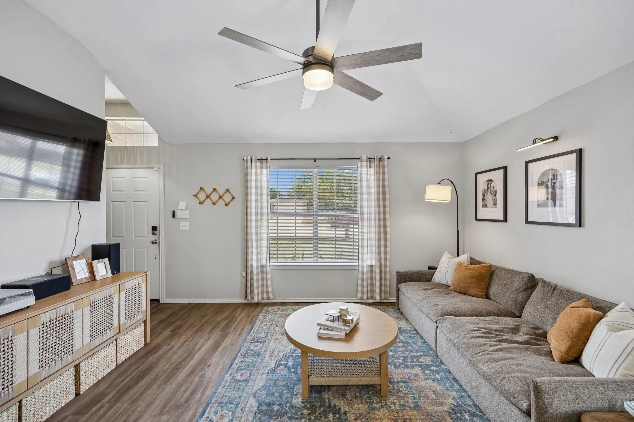Vaulted ceiling featuring a ceiling fan, wood-finish flooring, and a front entry door with transom window