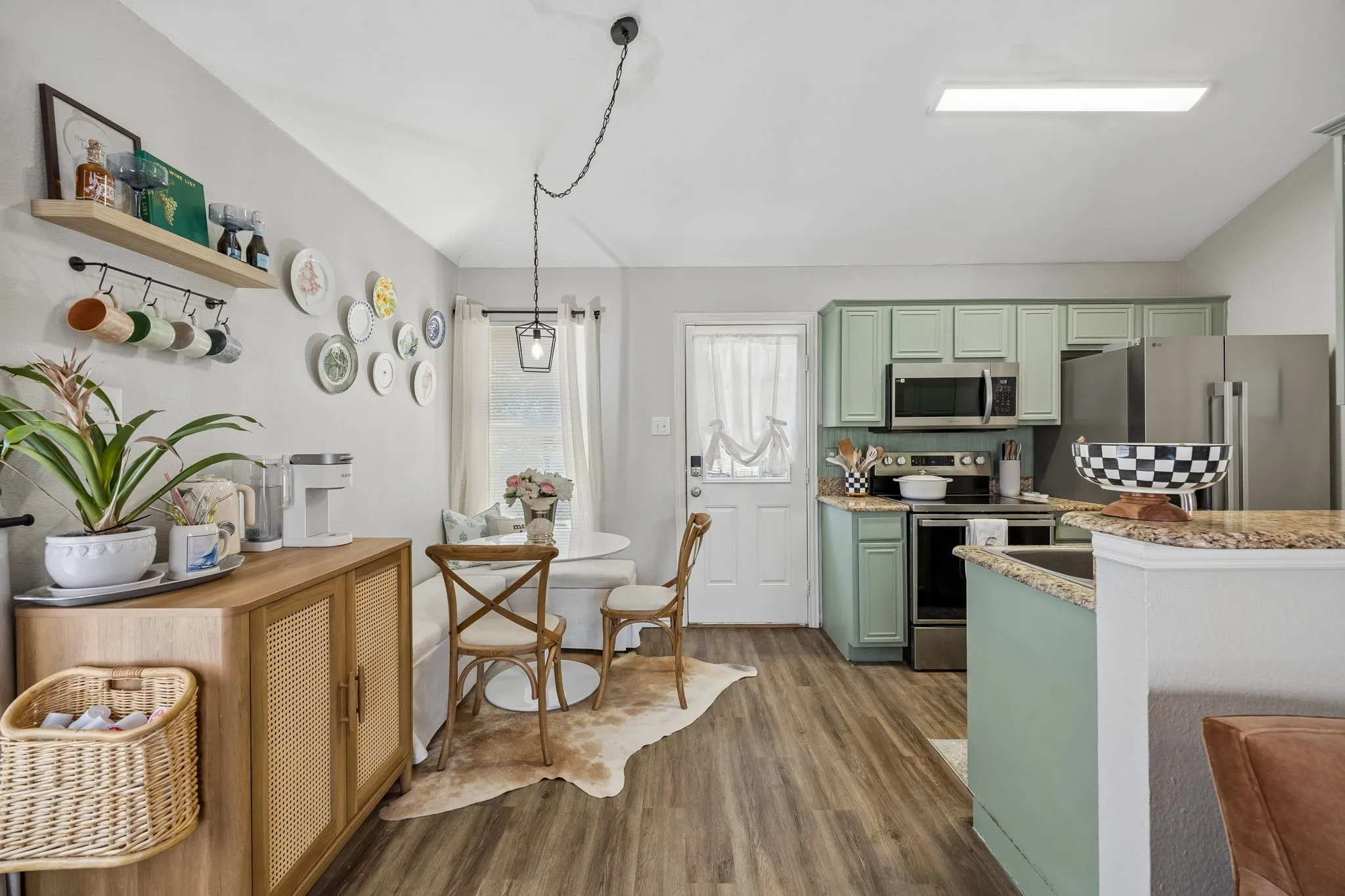 Kitchen featuring wood-finish flooring, light green cabinetry, stainless steel appliances, granite countertops, and a full-light rear door